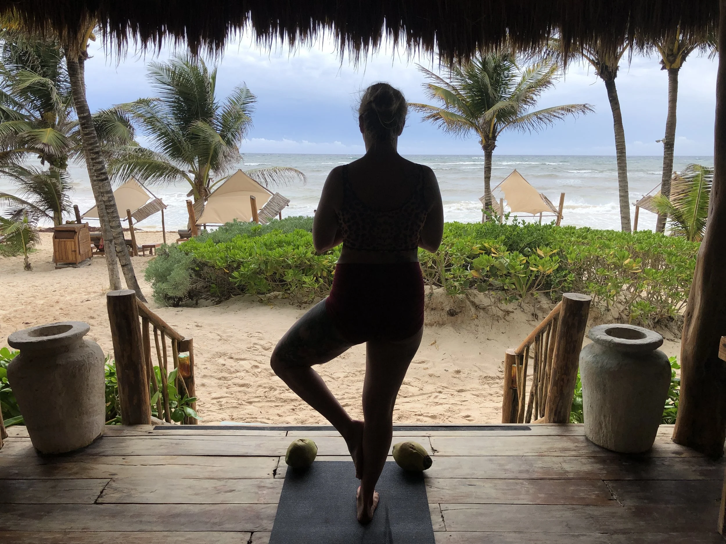 Brit practices Vrksasana on the beach in Tulum.