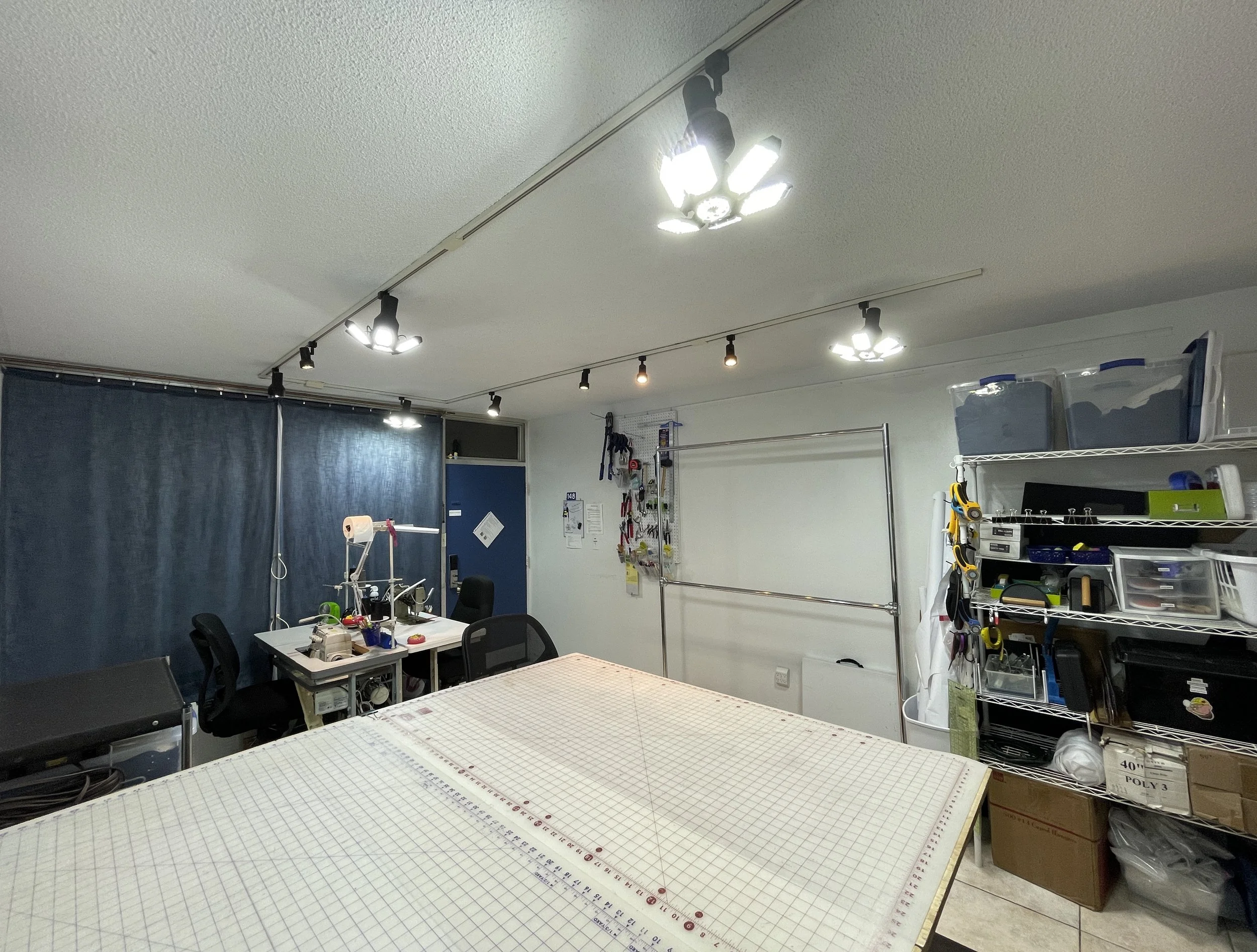 Interior room with large cutting table and two industrial sewing machines.