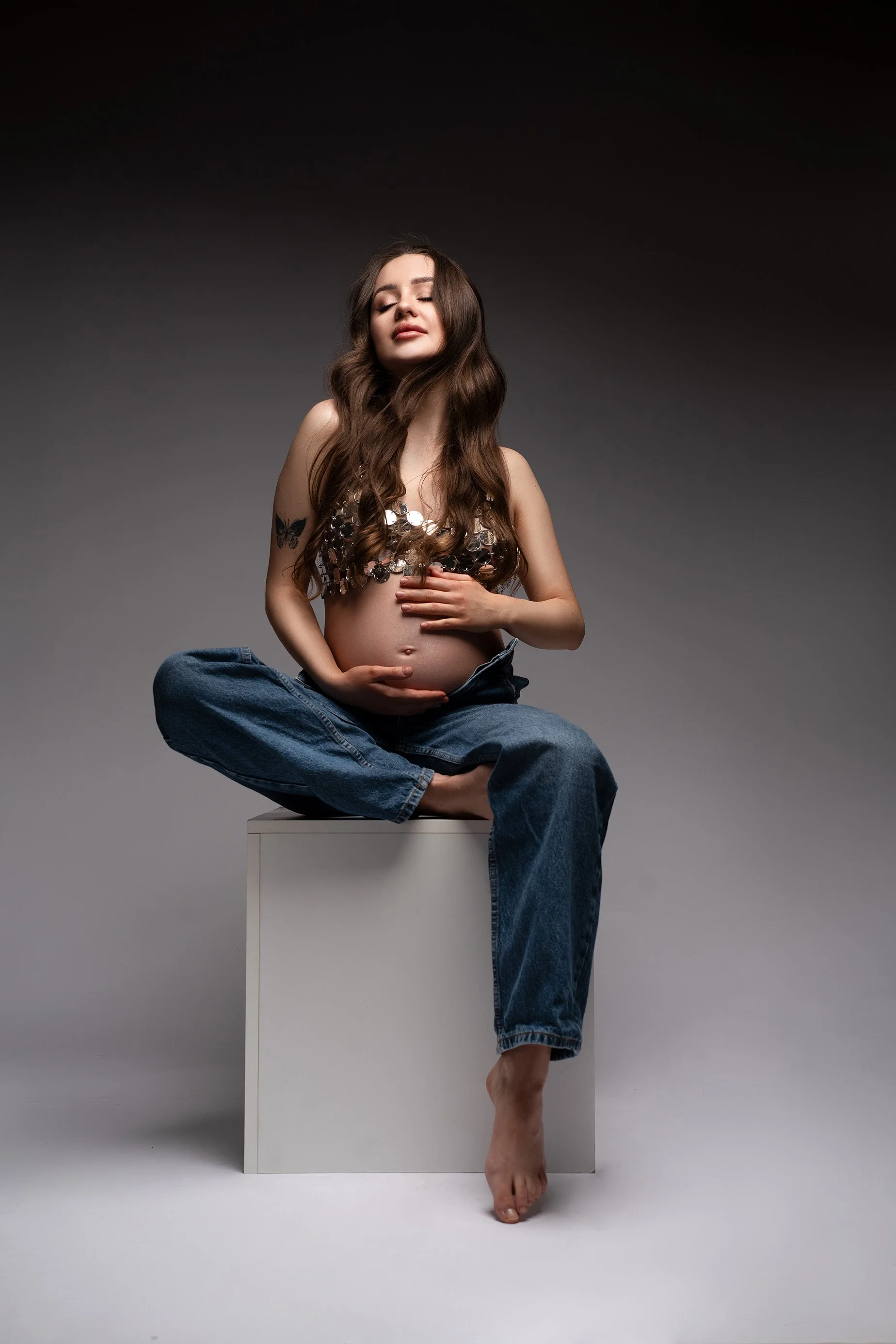 Sesja ciążowa w studio – kobiecy portret w jeansach na białym podeście 
