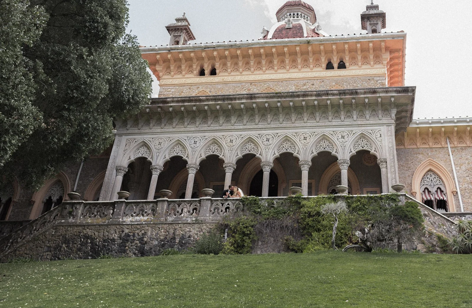 Couple standing together at Palácio de Monserrate in Sintra, Portugal, photographed with architectural arches and greenery in an editorial composition