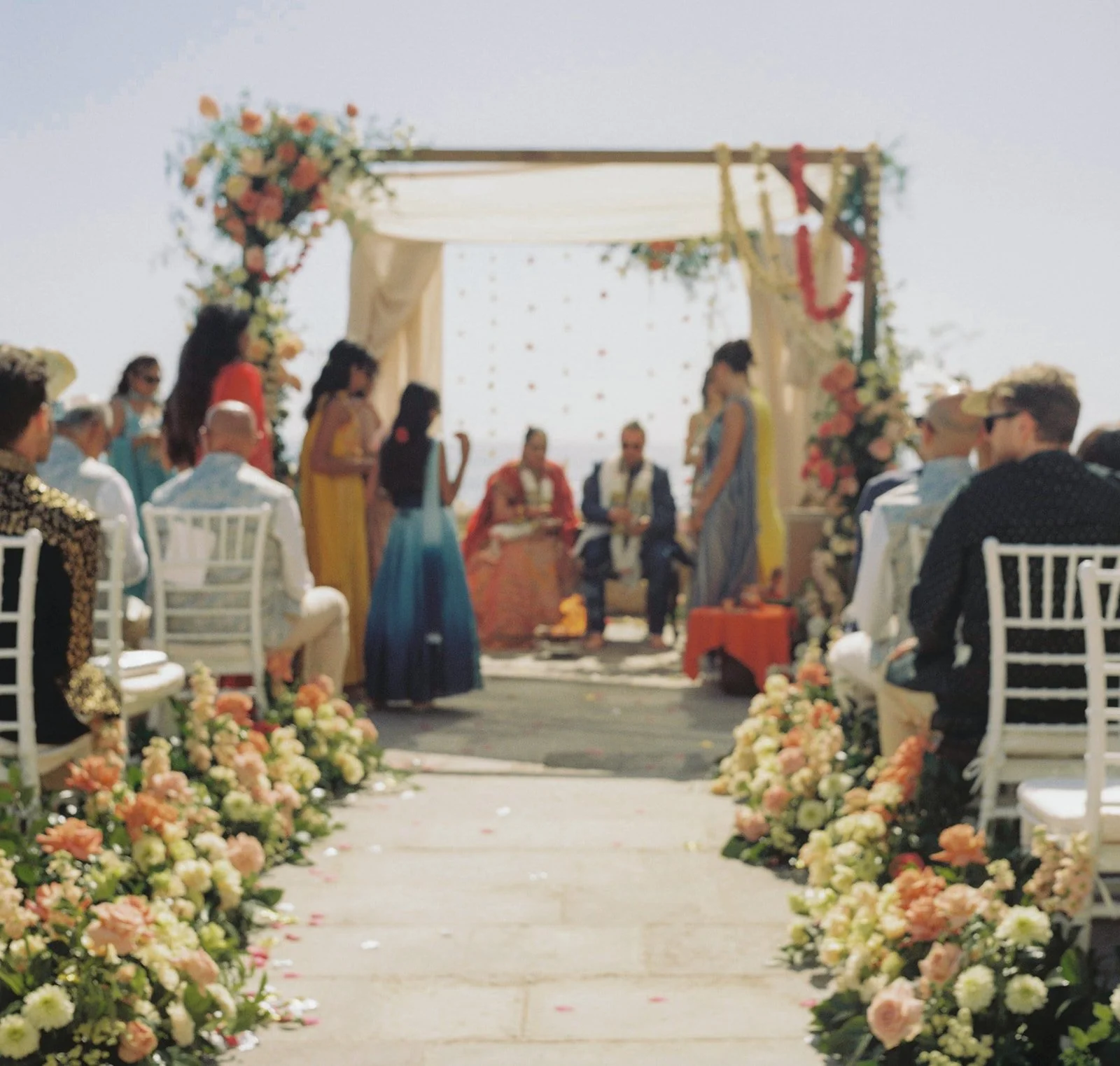 Outdoor ceremony setup with peach floral arrangements and white chiavari chairs at a Portugal destination wedding | by The Lopes Photography