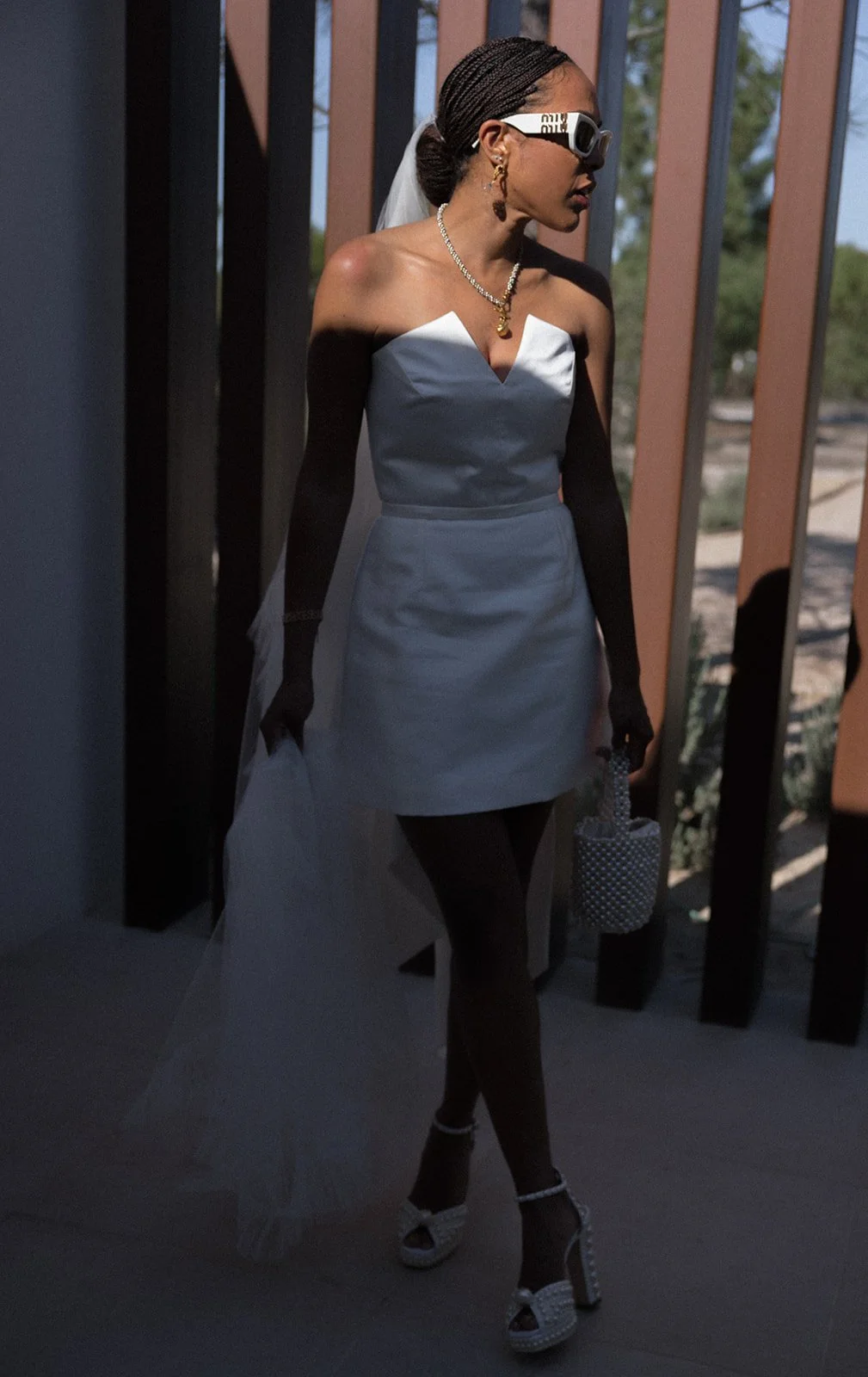 Bride in white mini dress walking through pergola with dramatic shadow pattern, Comporta private villa summer wedding | The Lopes Photography