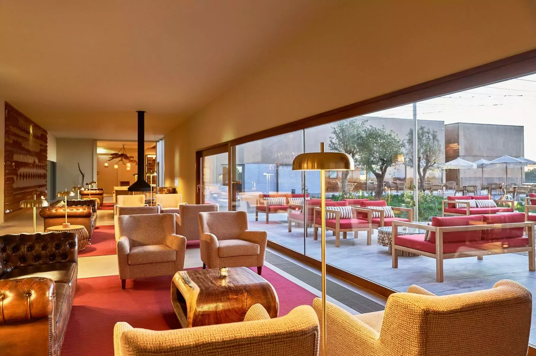 Praia do Canal Nature Retreat indoor lounge with floor-to-ceiling windows looking onto the outdoor terrace and red sofas – modern guest lounge for Algarve destination weddings.