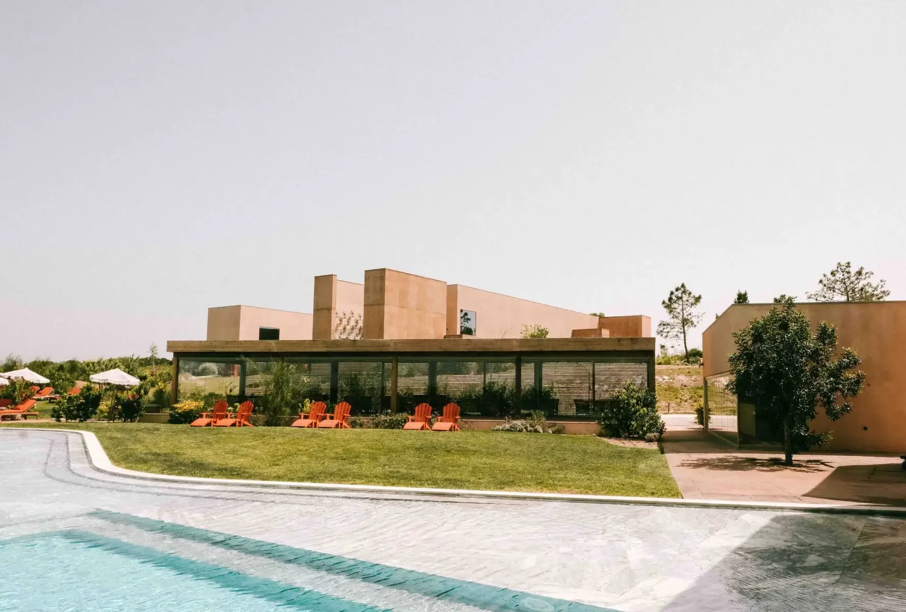 Praia do Canal Nature Retreat hotel and pool in Aljezur, Algarve, Portugal, modern minimalist architecture with lawn and water in the foreground, destination wedding venue.