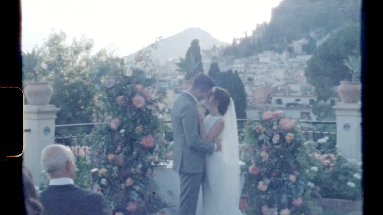 A Canadian couple kissing at the end of their intimate wedding ceremony, in Taormina, Sicily at the Belmond Grand Hotel Timeo. This is a screenshot from a Super 8 video.