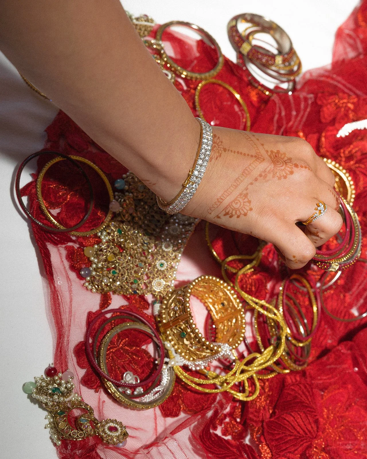 Hennaed hands with diamond bracelet in red embellished wedding attire, Fortaleza do Guincho, destination wedding photography by The Lopes Photography