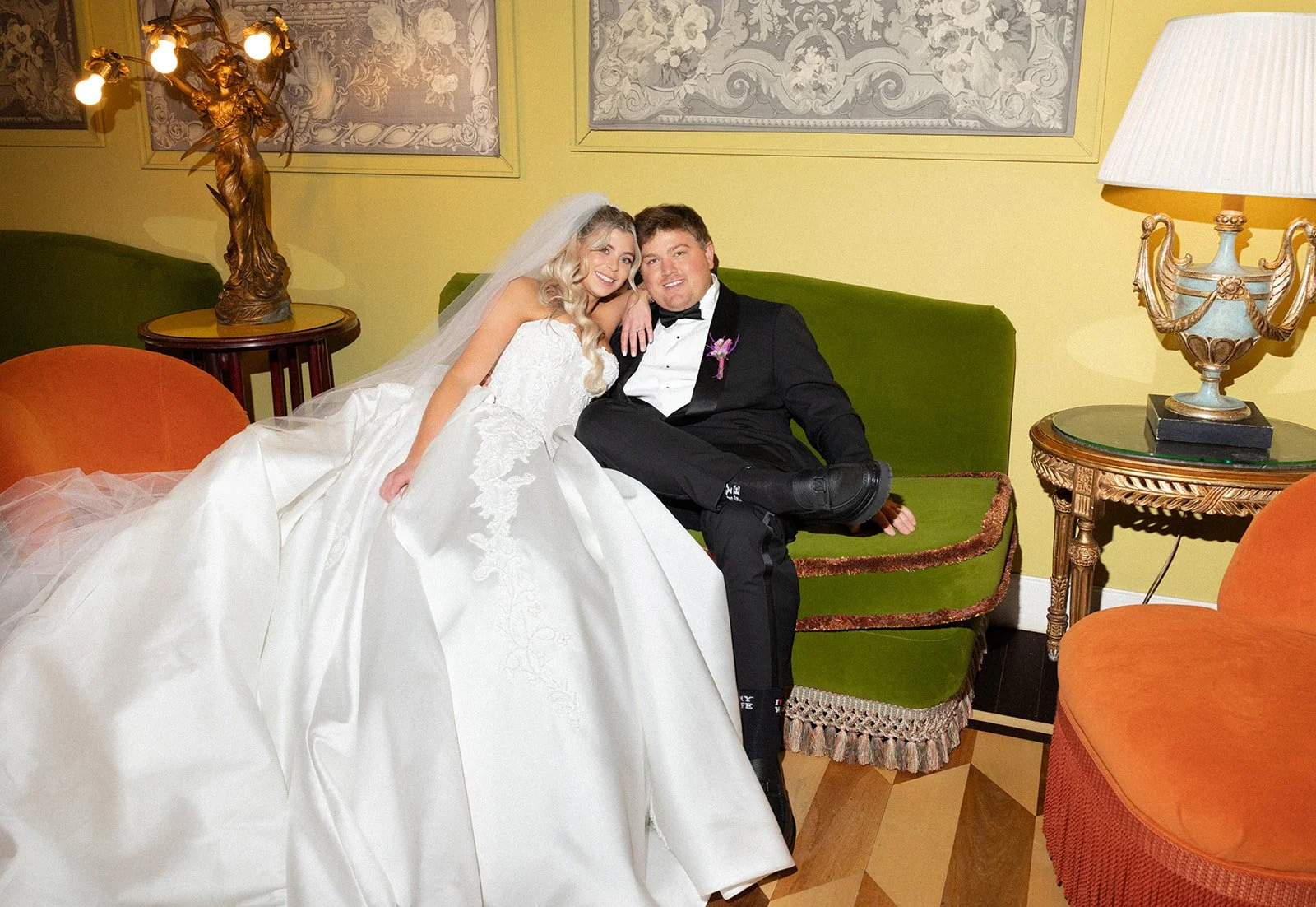 Bride and groom seated together on a green velvet sofa in an ornately decorated suite at Grand Hotel Tremezzo, Lake Como | The Lopes Photography