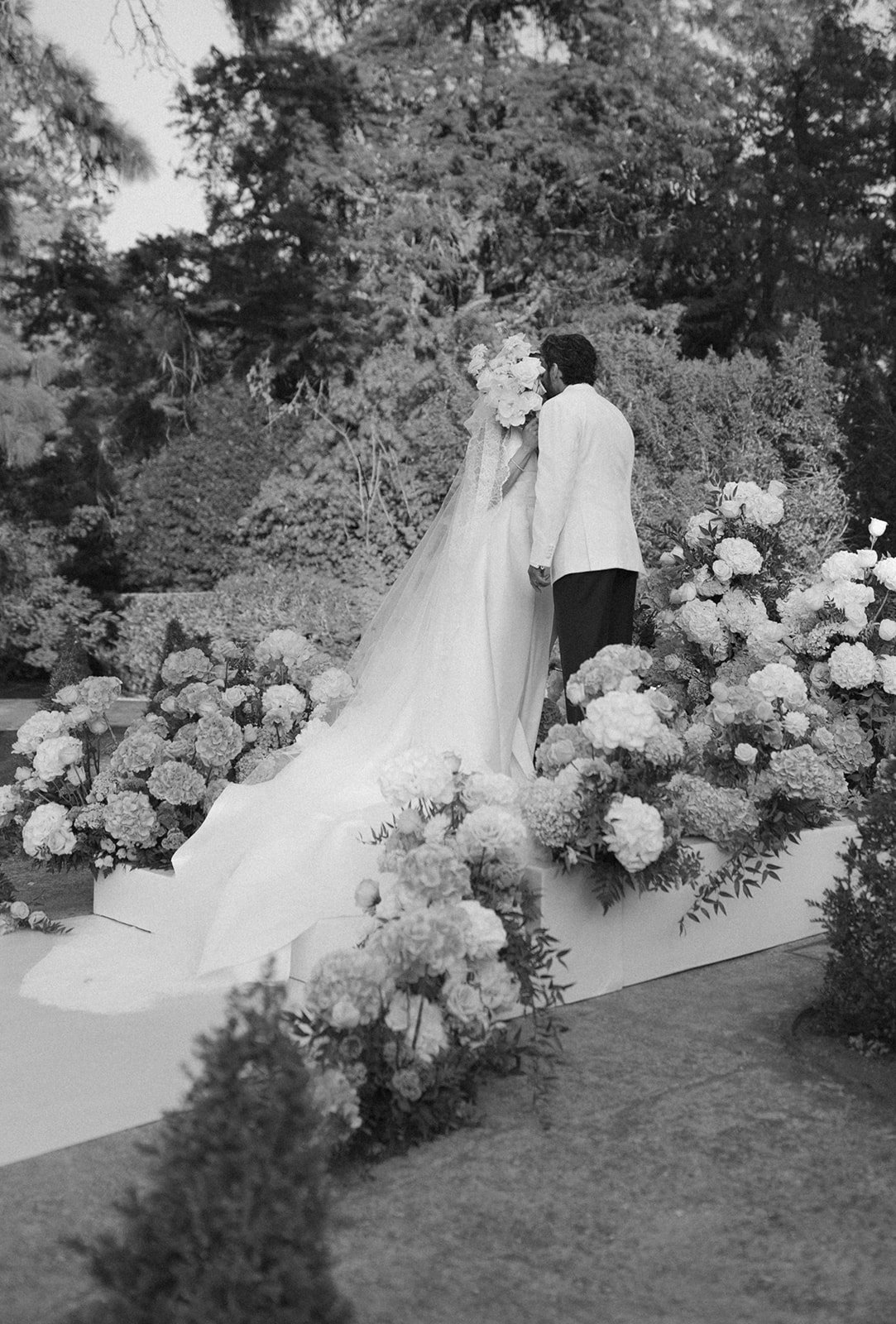 Newlyweds kissing with white hydrangea arrangements at Queluz, intimate ceremony editorial photography by The Lopes Photography