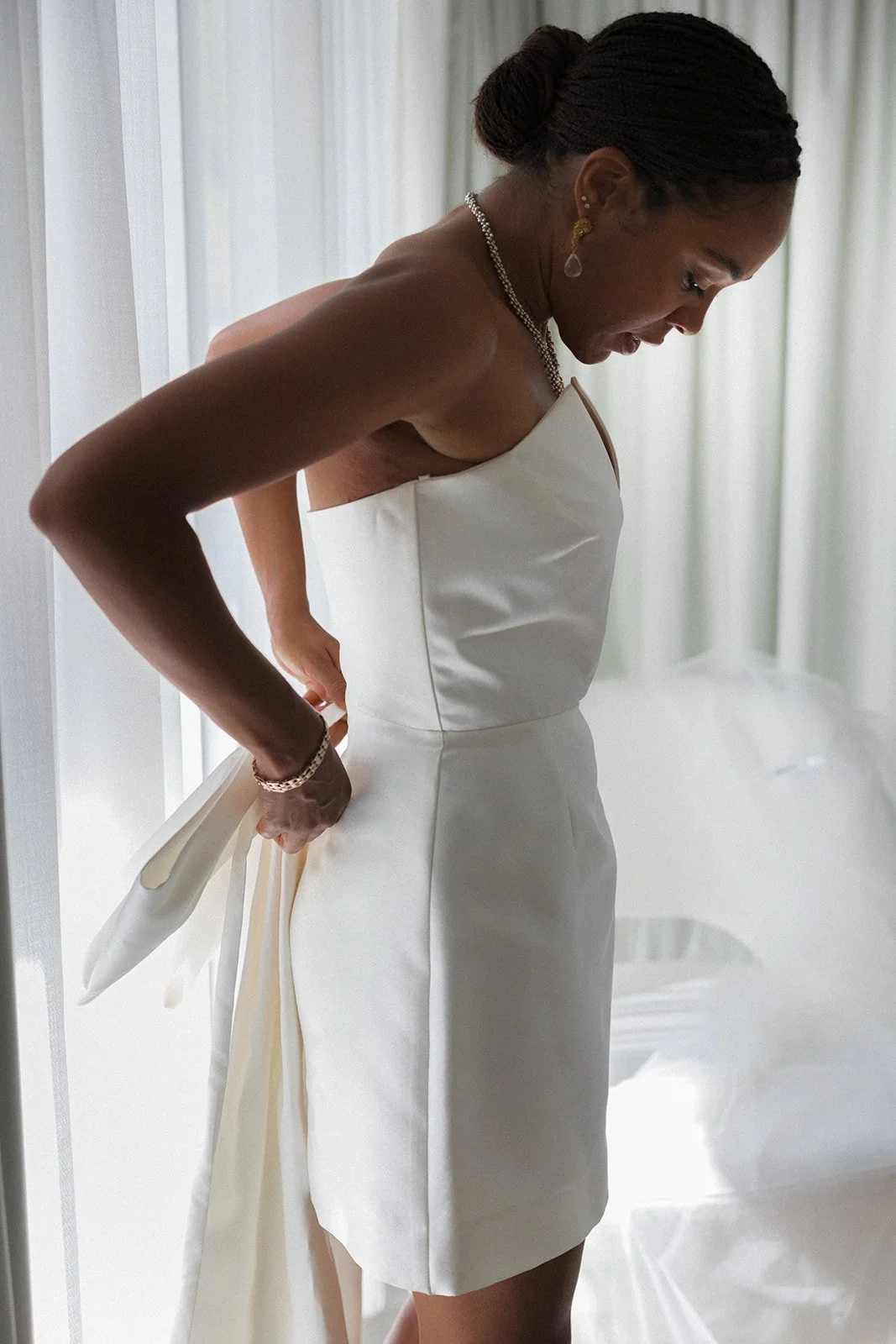 Bride adjusting dress by window, Spatia Comporta, wedding photography by The Lopes Photography, published in Together Journal