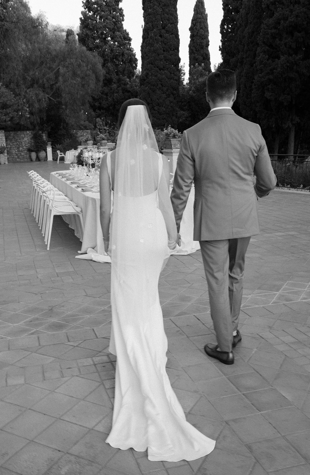Couple walking hand in hand past a terrace table, Belmond Grand Hotel Timeo, wedding photography by The Lopes Photography