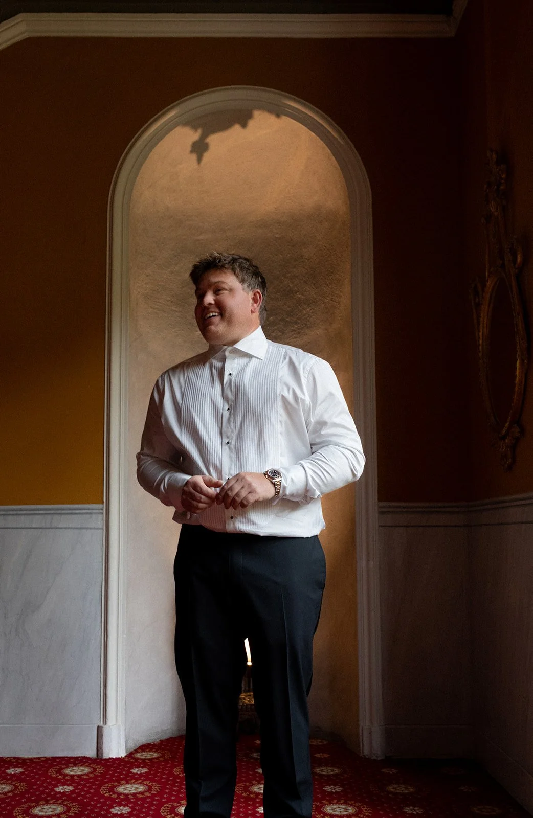 Groom adjusting cufflinks in an archway at Grand Hotel Tremezzo, Lake Como, Italy, destination wedding photography — The Lopes Photography
