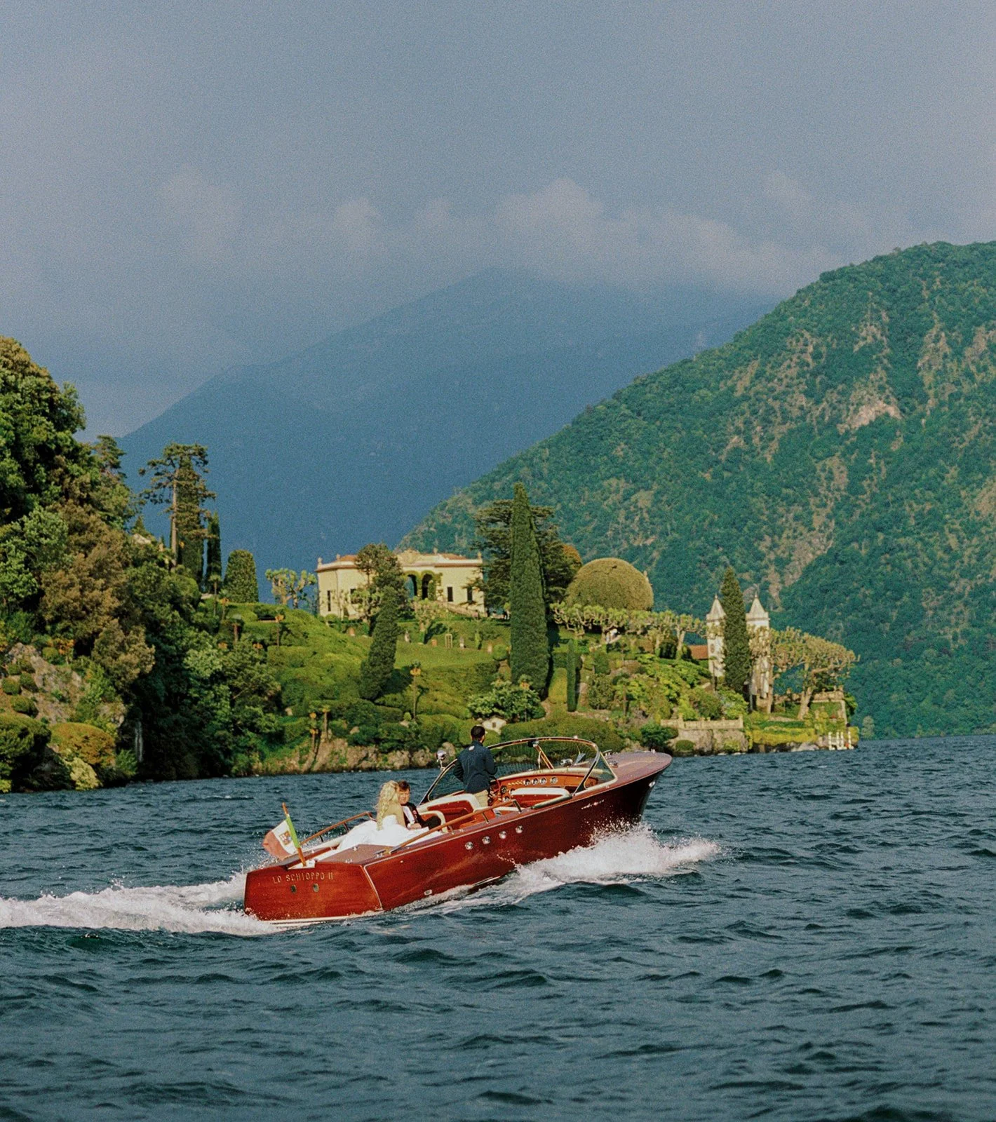 Couple crossing Lake Como by classic wooden speedboat to Villa Balbiano, elopement photography by The Lopes Photography