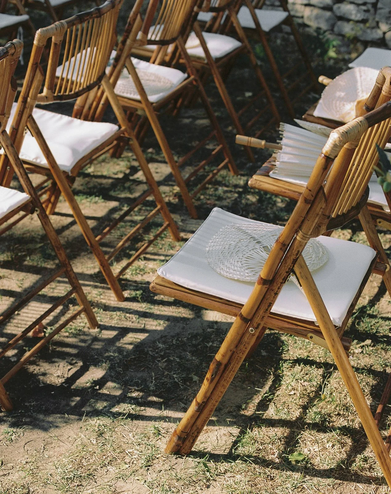 Outdoor ceremony setup at Le Grand Banc with bamboo chairs and wicker fans, Provence | The Lopes Photography