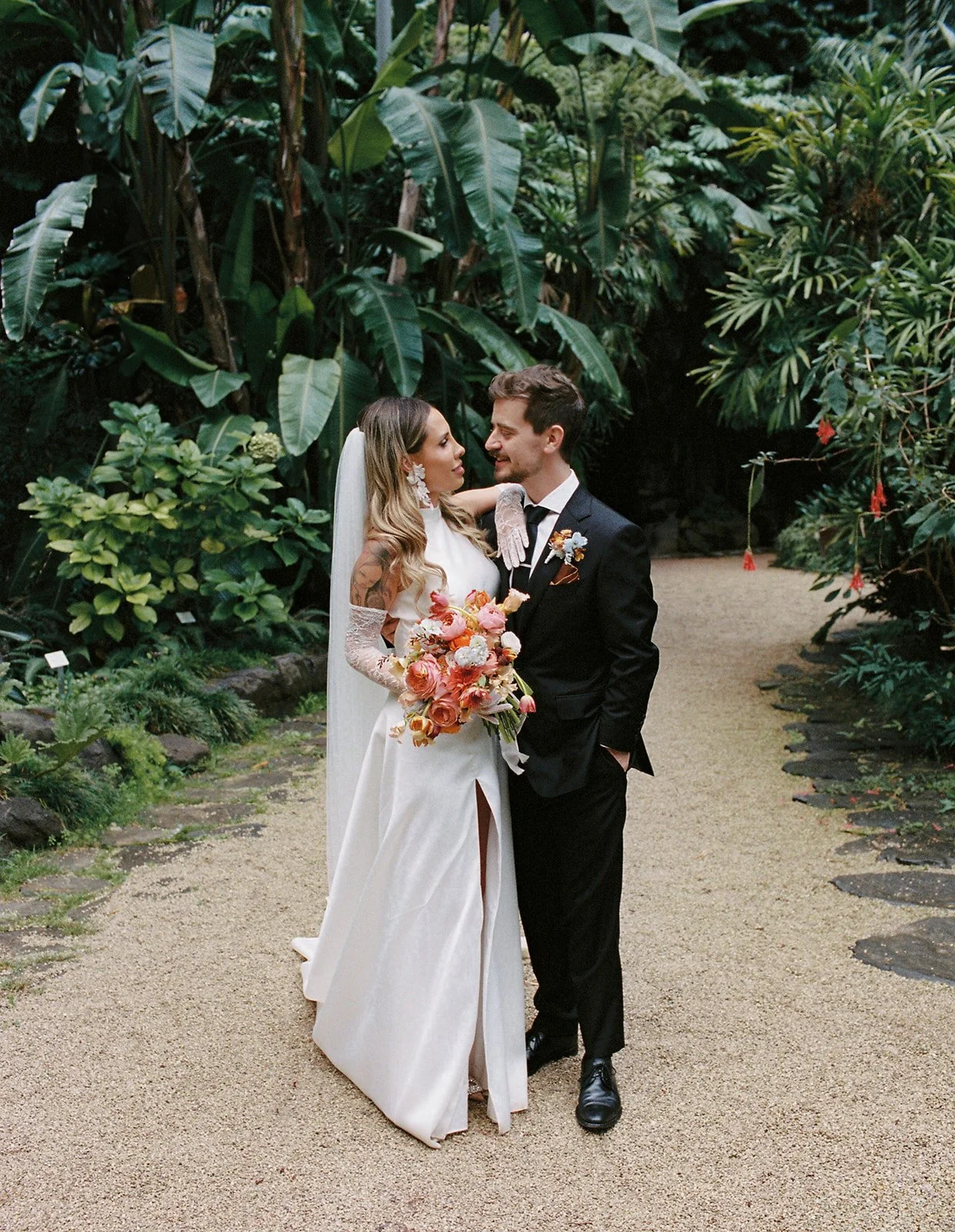 Bride and groom smiling at each other on a garden path at their Estufa Fria destination wedding in Lisbon | The Lopes Photography