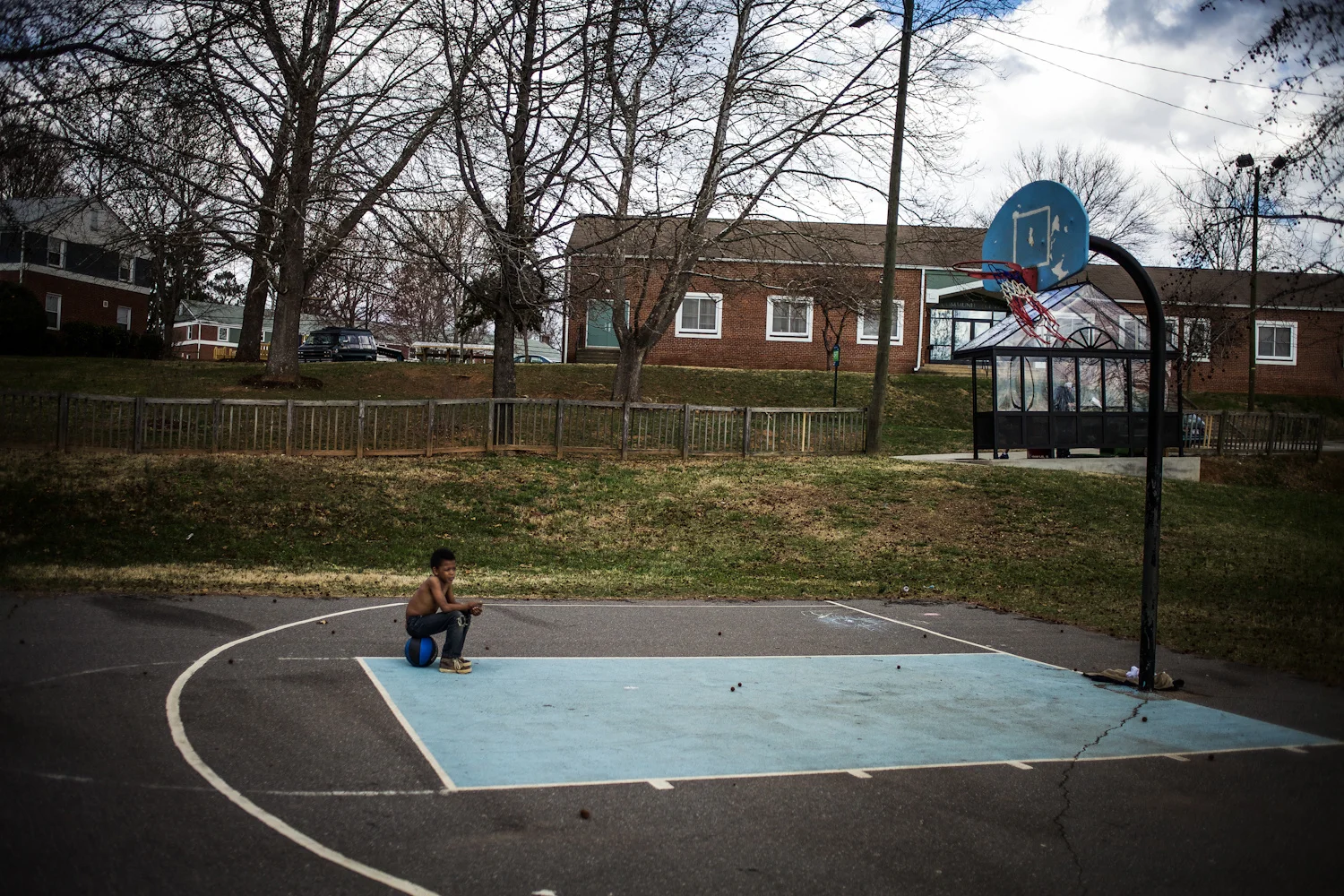 George Etheredge . March 12, 2014. A boy sits on his basketball at Pisgah View apartments, Asheville, Buncombe County, North Carolina.