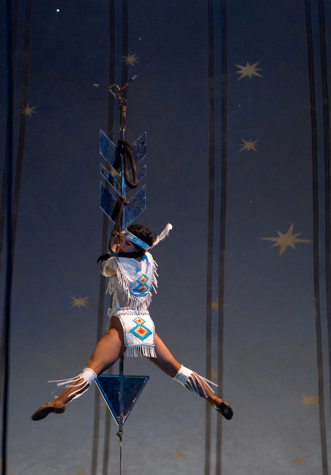 Lauren Pond . July 20, 2014. A performer dressed as a Native American dances on a giant metal arrow dangling from the top of a circus tent during the Carson and Barnes Circus. Stewart, Athens County, Ohio.