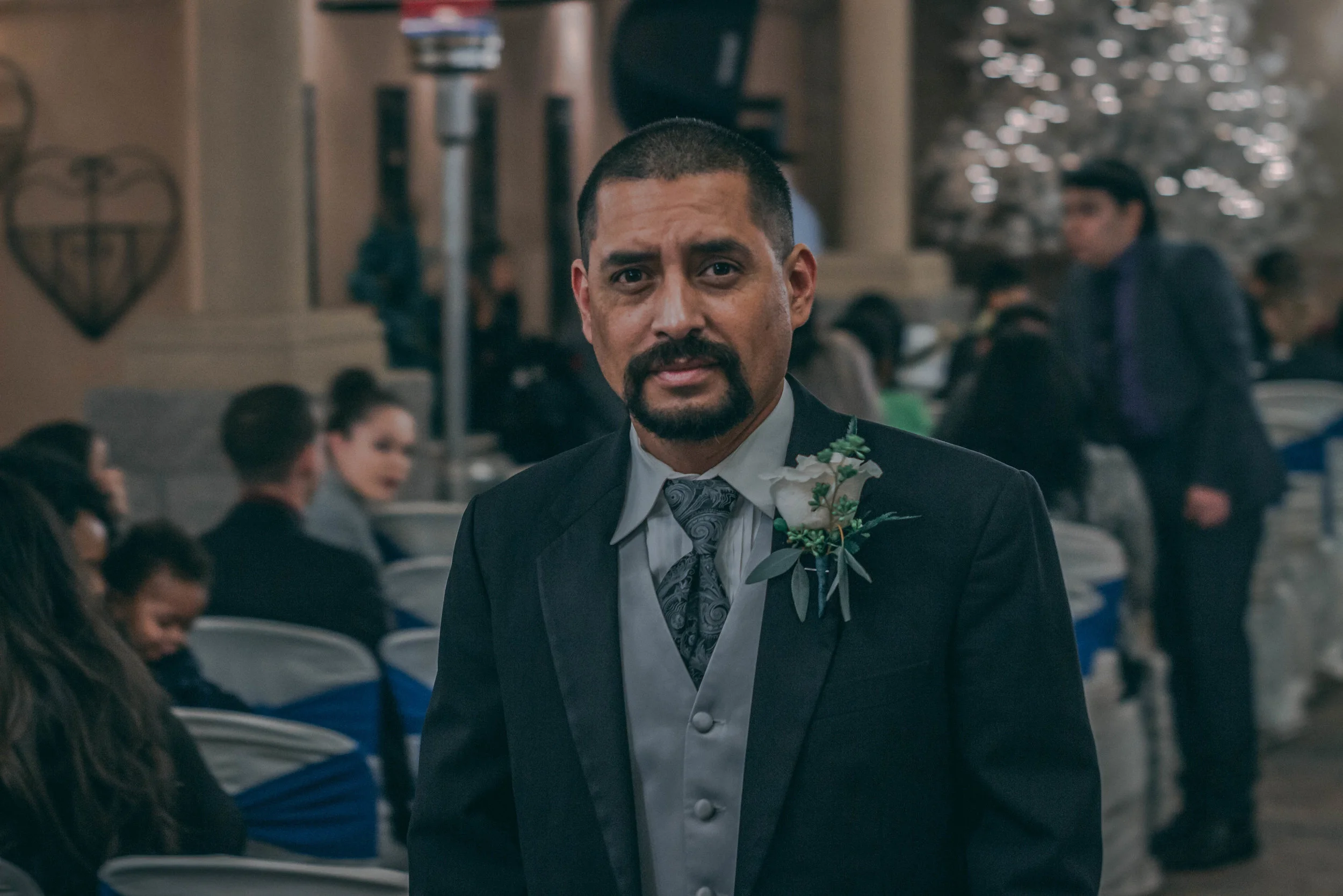 Portrait of a man in a wedding vest and boutonniere at an indoor reception, wedding photography by Everlux Photo Co.