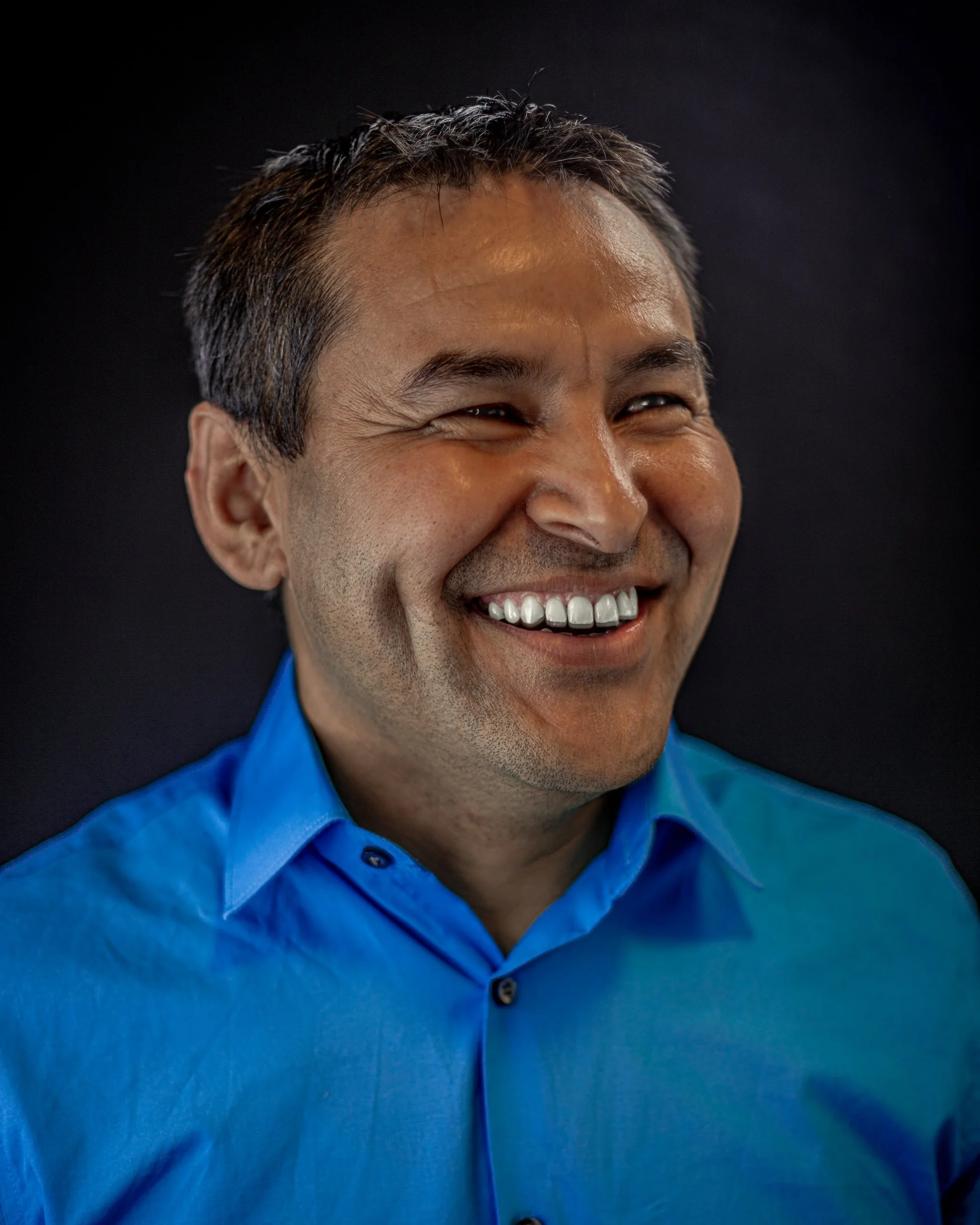 Smiling studio portrait of a man in a blue shirt, portrait photography by Everlux Photo Co.
