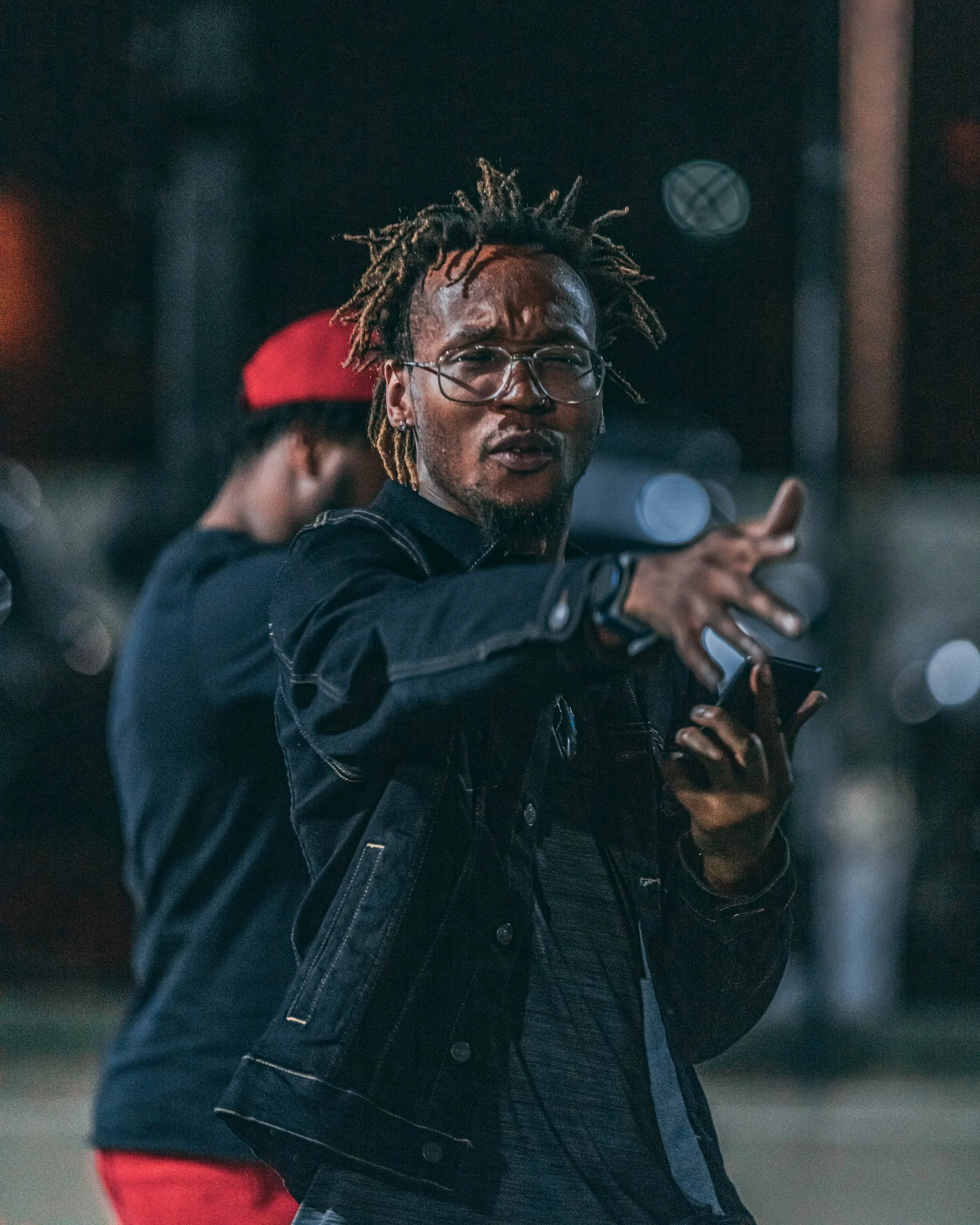 Expressive nighttime portrait of a man with dreadlocks gesturing with his hands, portrait photography by Everlux Photo Co.