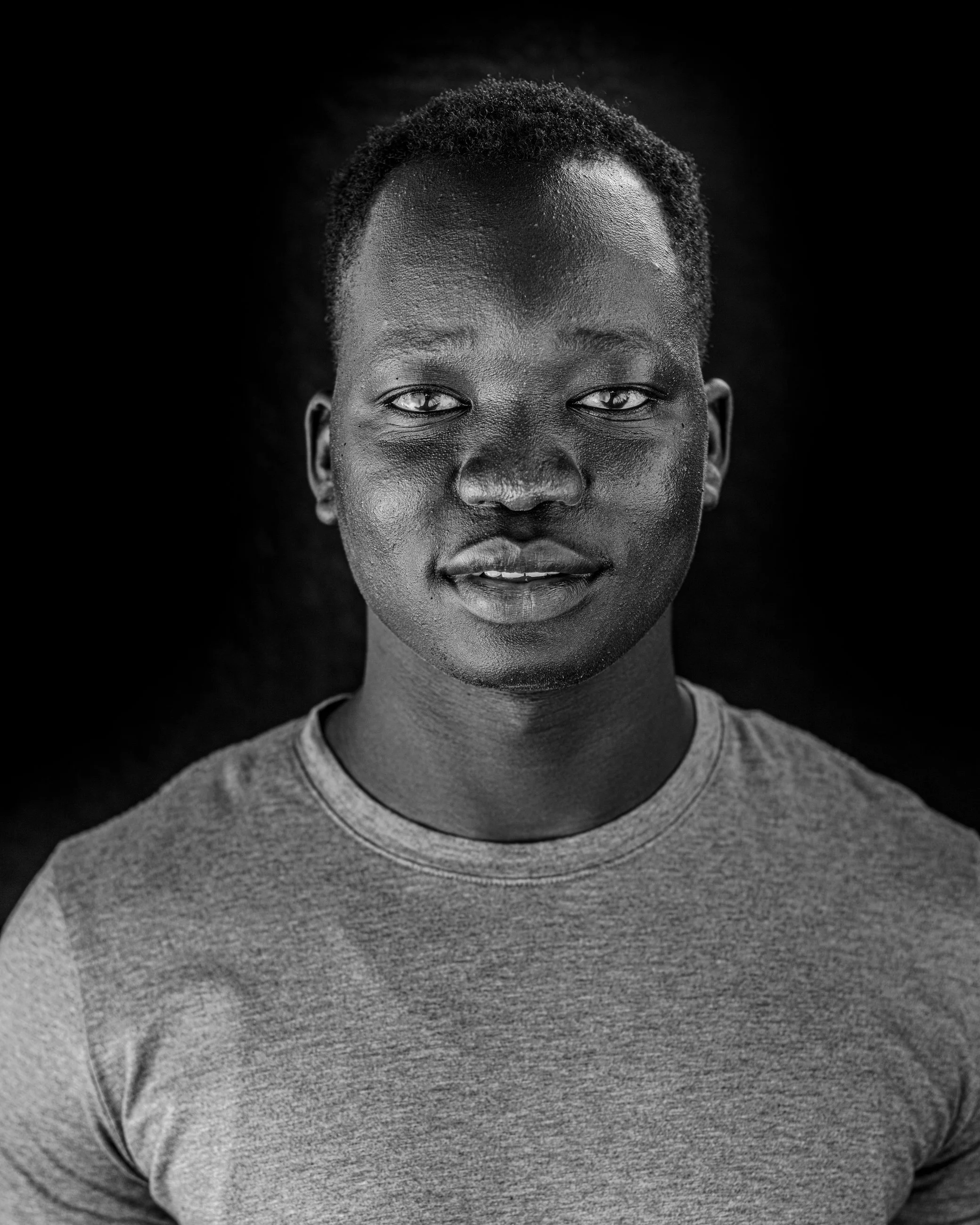 High-contrast black and white studio portrait of a man with a direct gaze, portrait photography by Everlux Photo Co.