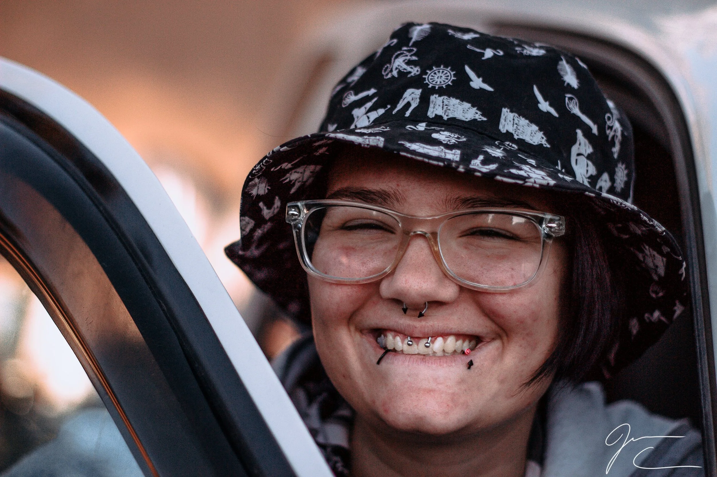 Close-up portrait of a smiling person wearing a patterned bucket hat and glasses, portrait photography by Everlux Photo Co.