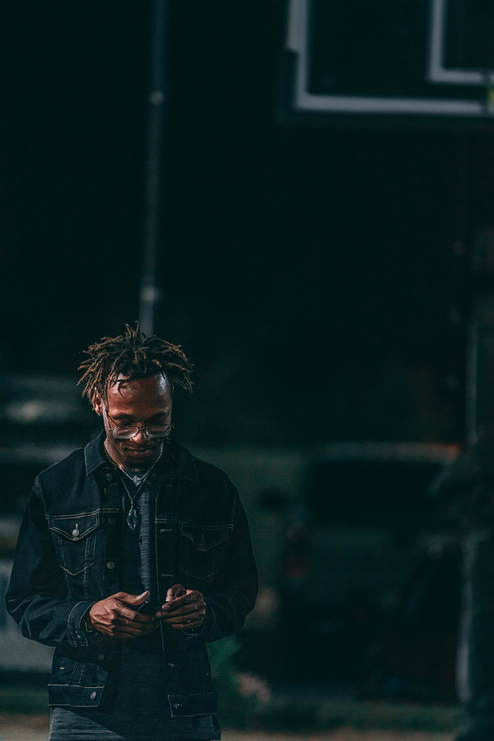 Nighttime portrait of a man at a basketball court checking his phone, portrait photography by Everlux Photo Co.