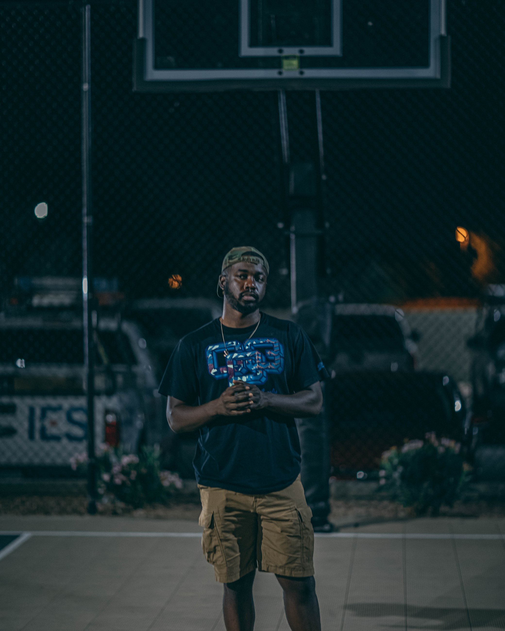 Candid portrait of a man standing at a basketball court at dusk, portrait photography by Everlux Photo Co.