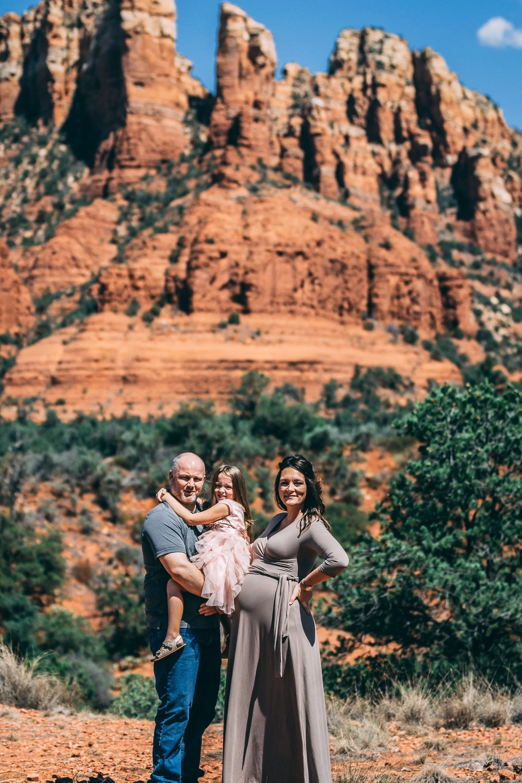 Family portrait against dramatic red rock desert formations, family photography by Everlux Photo Co.