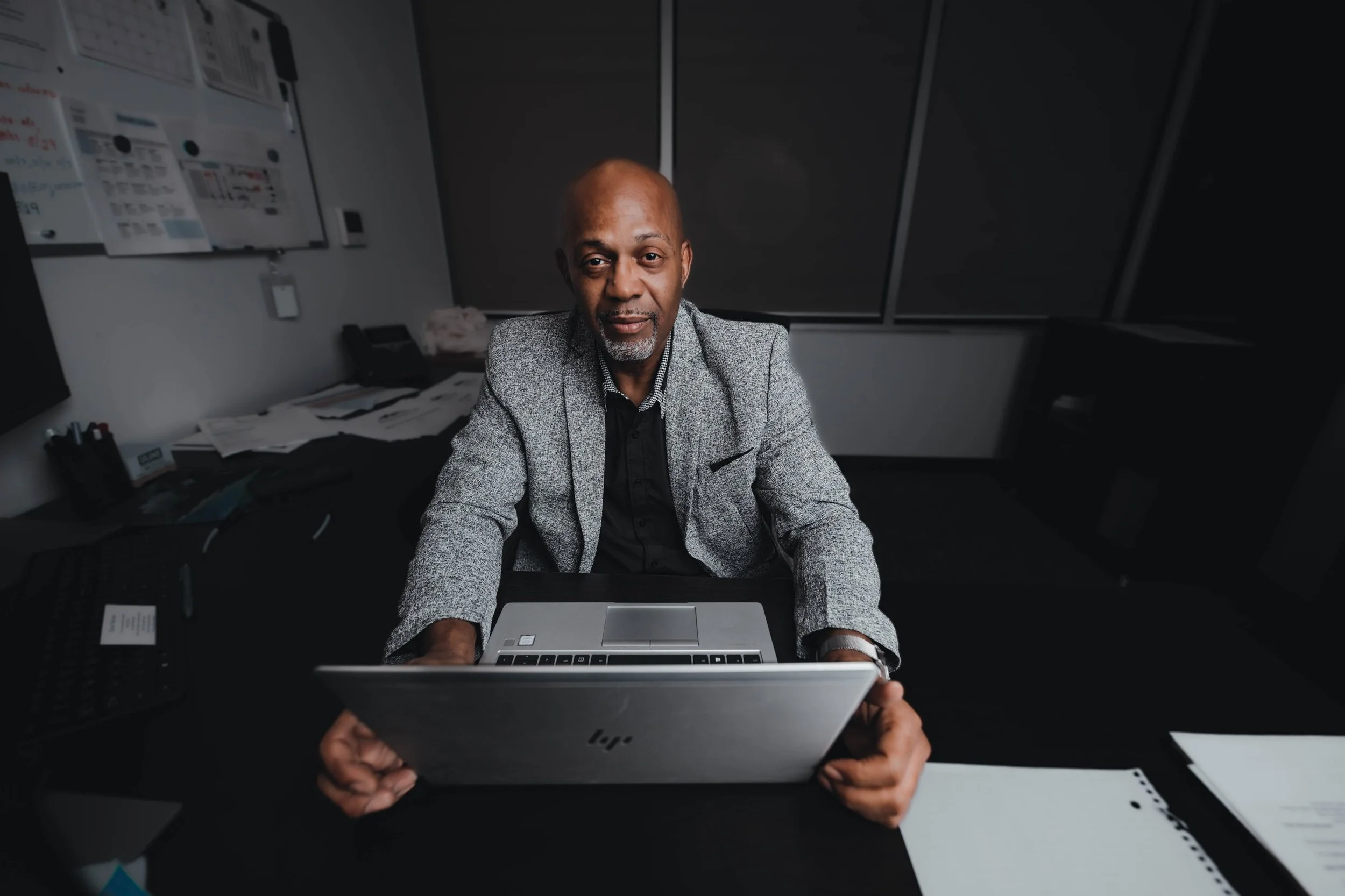 Environmental business portrait of a man in a blazer working at a desk in an office, headshot photography by Everlux Photo Co.
