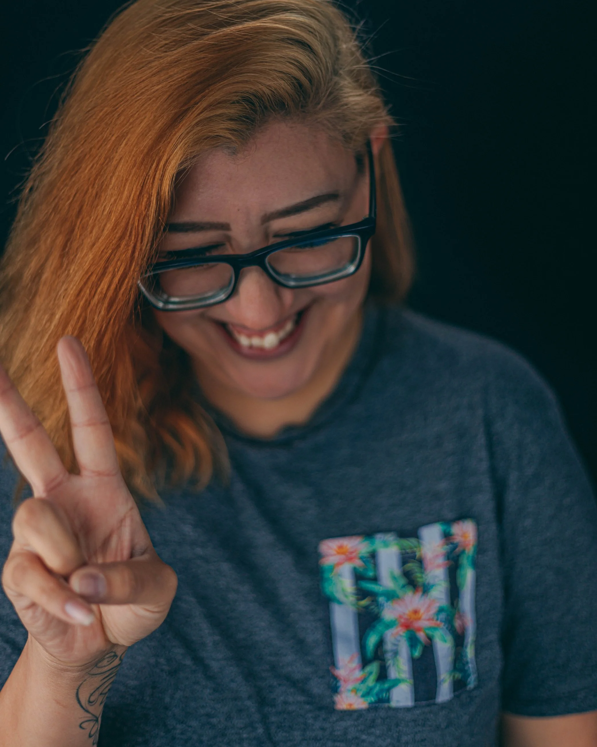Playful studio portrait of a woman with glasses making a peace sign, portrait photography by Everlux Photo Co.