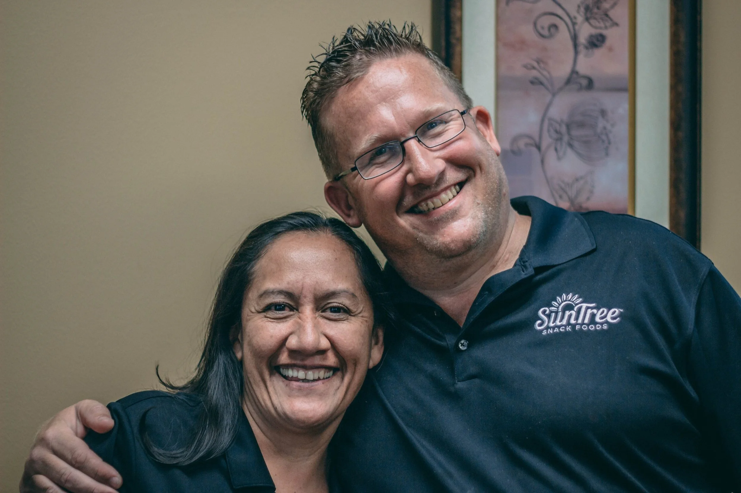 Team headshot of two coworkers in matching branded polo shirts smiling together, business headshot photography by Everlux Photo Co.