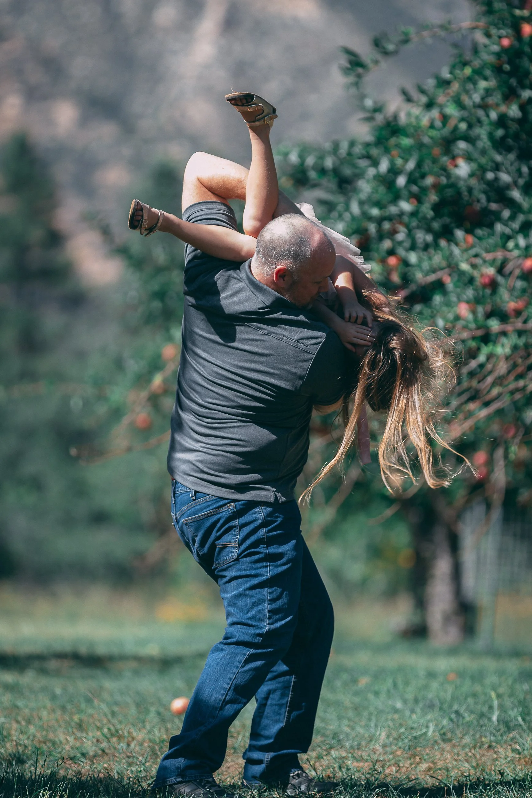 Playful outdoor family portrait of a man lifting a child overhead, family photography by Everlux Photo Co.