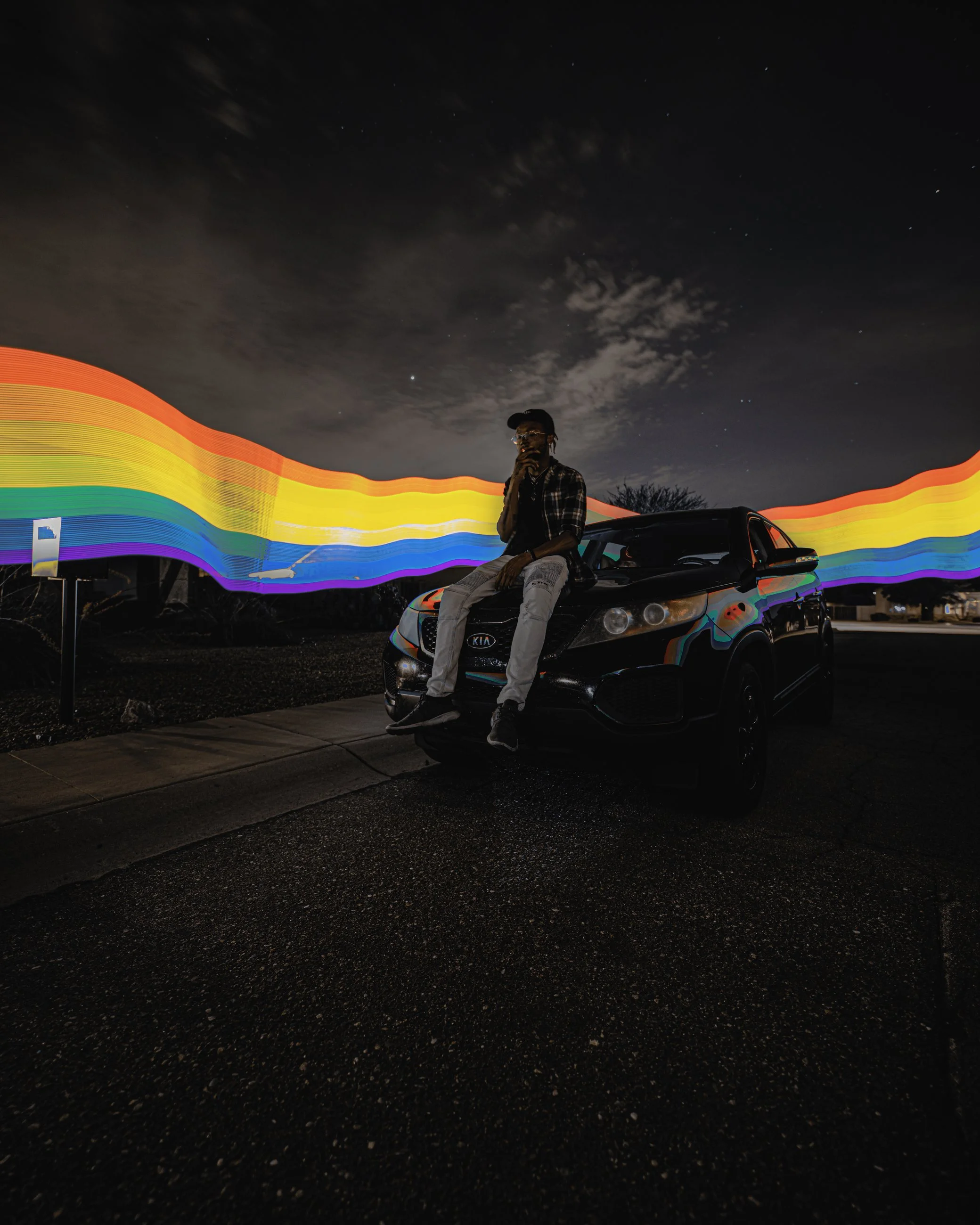 Artistic nighttime portrait with colorful rainbow smoke trailing across the sky beside a parked car, portrait photography by Everlux Photo Co.