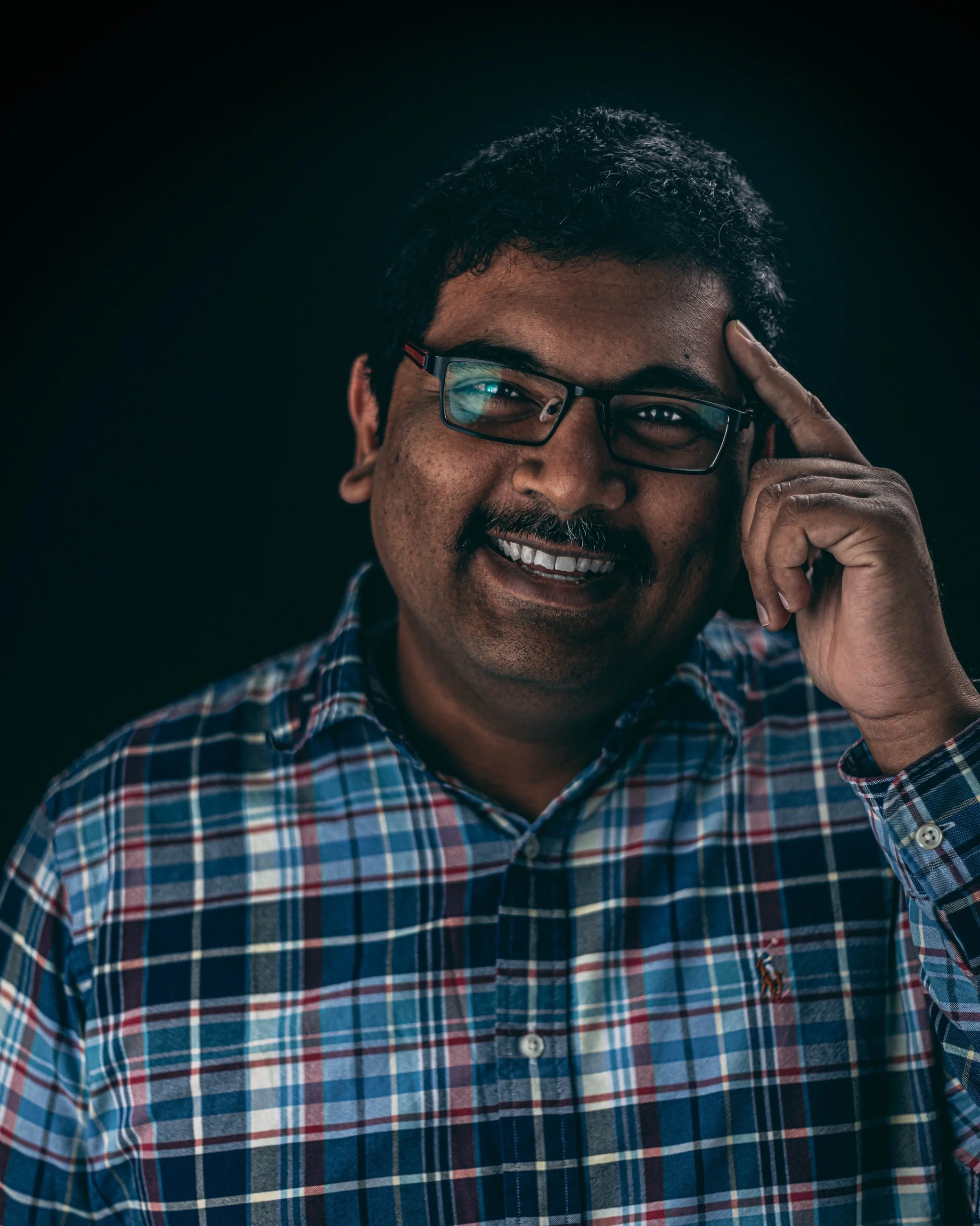Studio portrait of a smiling man in a plaid flannel shirt with glasses, portrait photography by Everlux Photo Co.