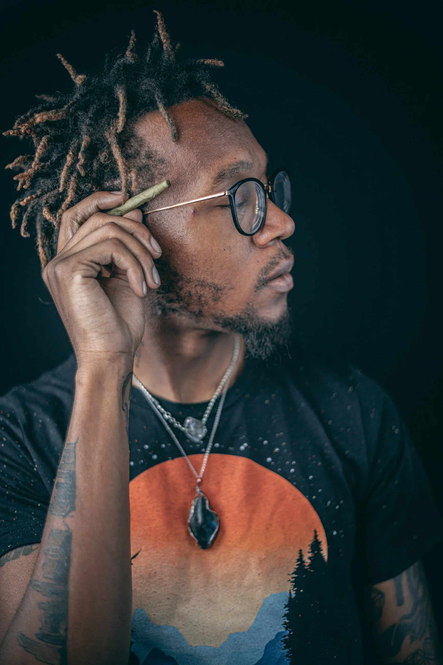 Studio portrait of a man in glasses wearing a graphic t-shirt and necklace, portrait photography by Everlux Photo Co.