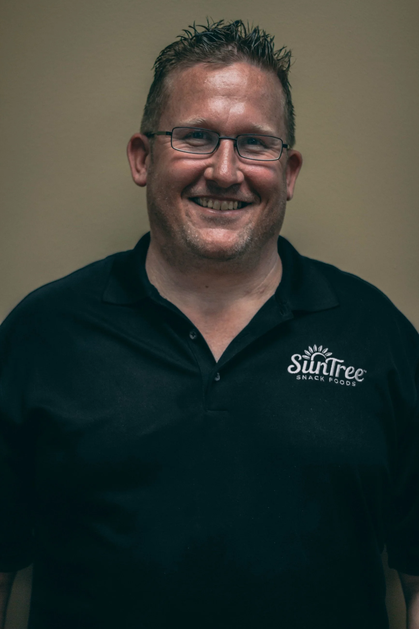 Professional headshot of a smiling man in a branded polo shirt, business headshot photography by Everlux Photo Co.