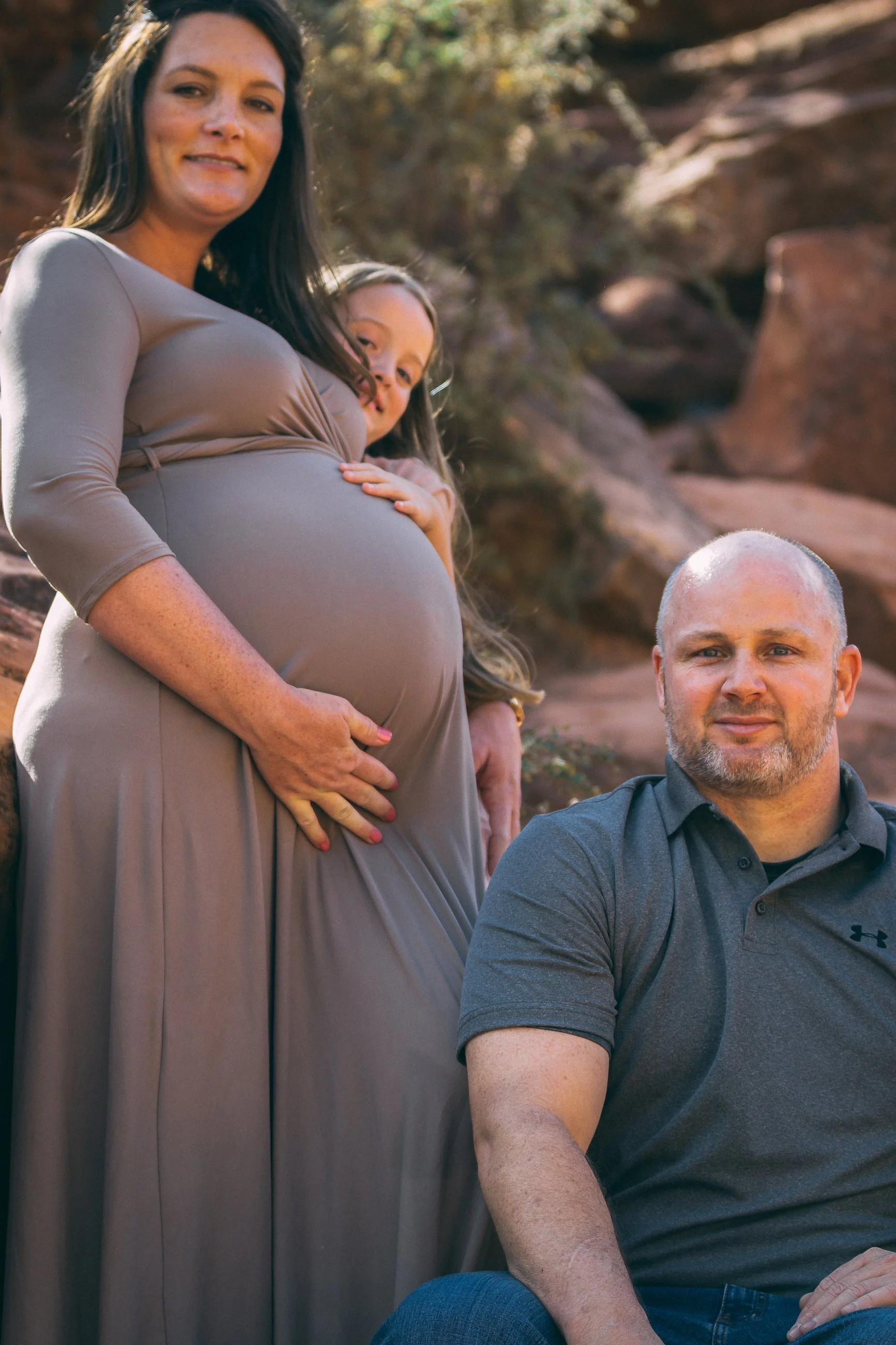 Maternity portrait of an expecting couple outdoors against red rock terrain, maternity photography by Everlux Photo Co.