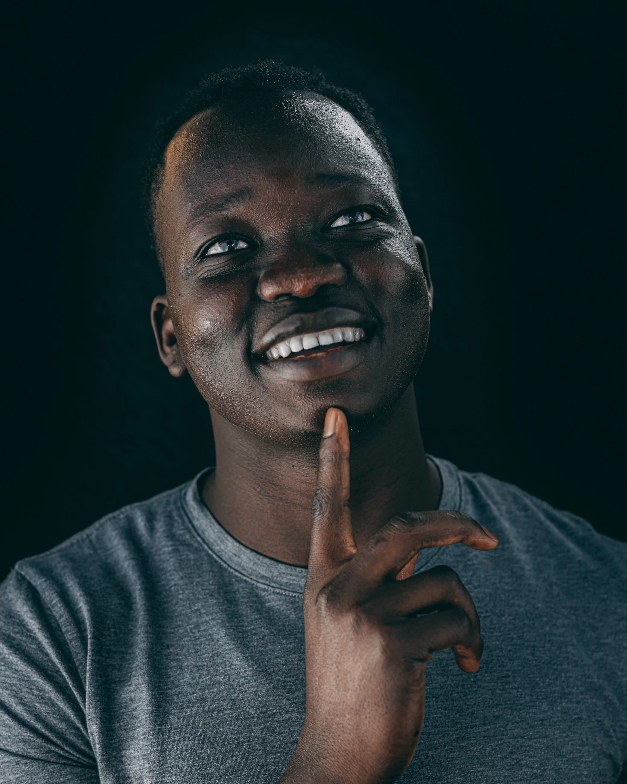 Playful studio portrait of a smiling man with his finger to his chin, portrait photography by Everlux Photo Co.