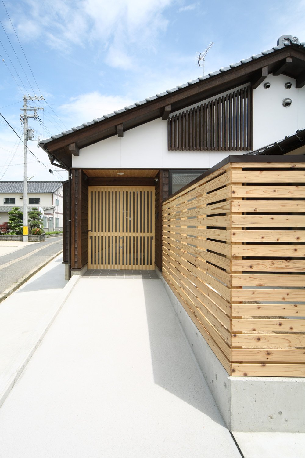 杉板の塀と玄関戸。白い漆喰の外壁に瓦屋根の外観
