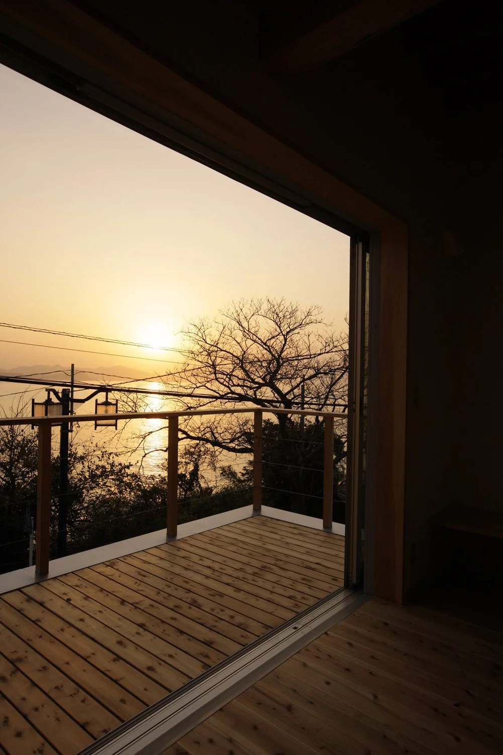 バルコニー手摺の向こうに見える海の景色と沈む夕日