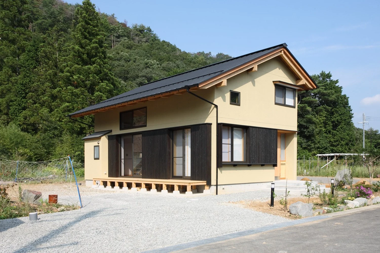 切妻屋根の家。外壁の２面に設けられた窓には黒い戸袋がついている