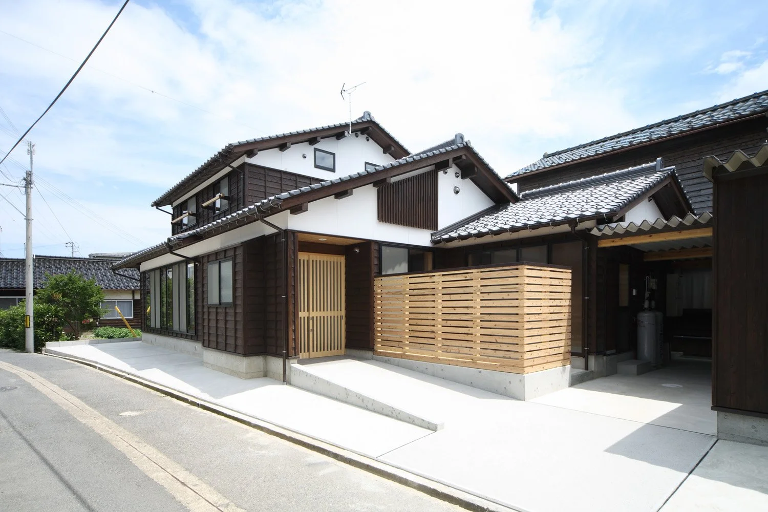 瓦屋根に漆喰、押え縁板張りの外観を持つ２階建て住宅