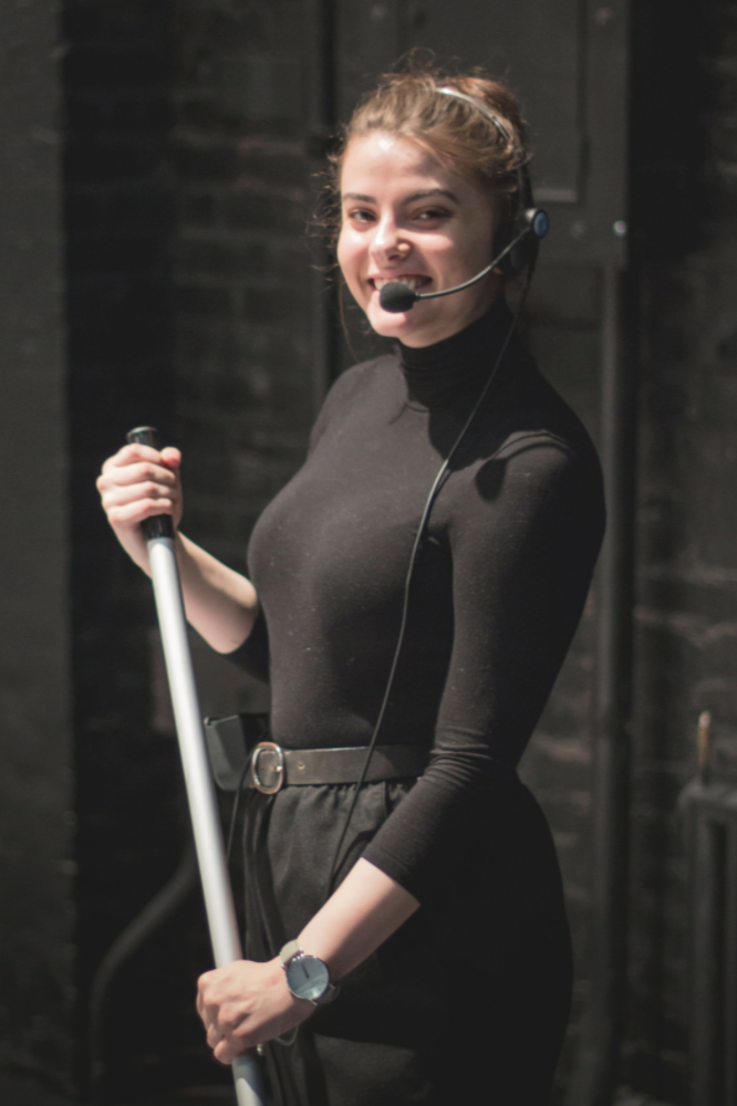 Woman wearing a headset and sweeping backstage.