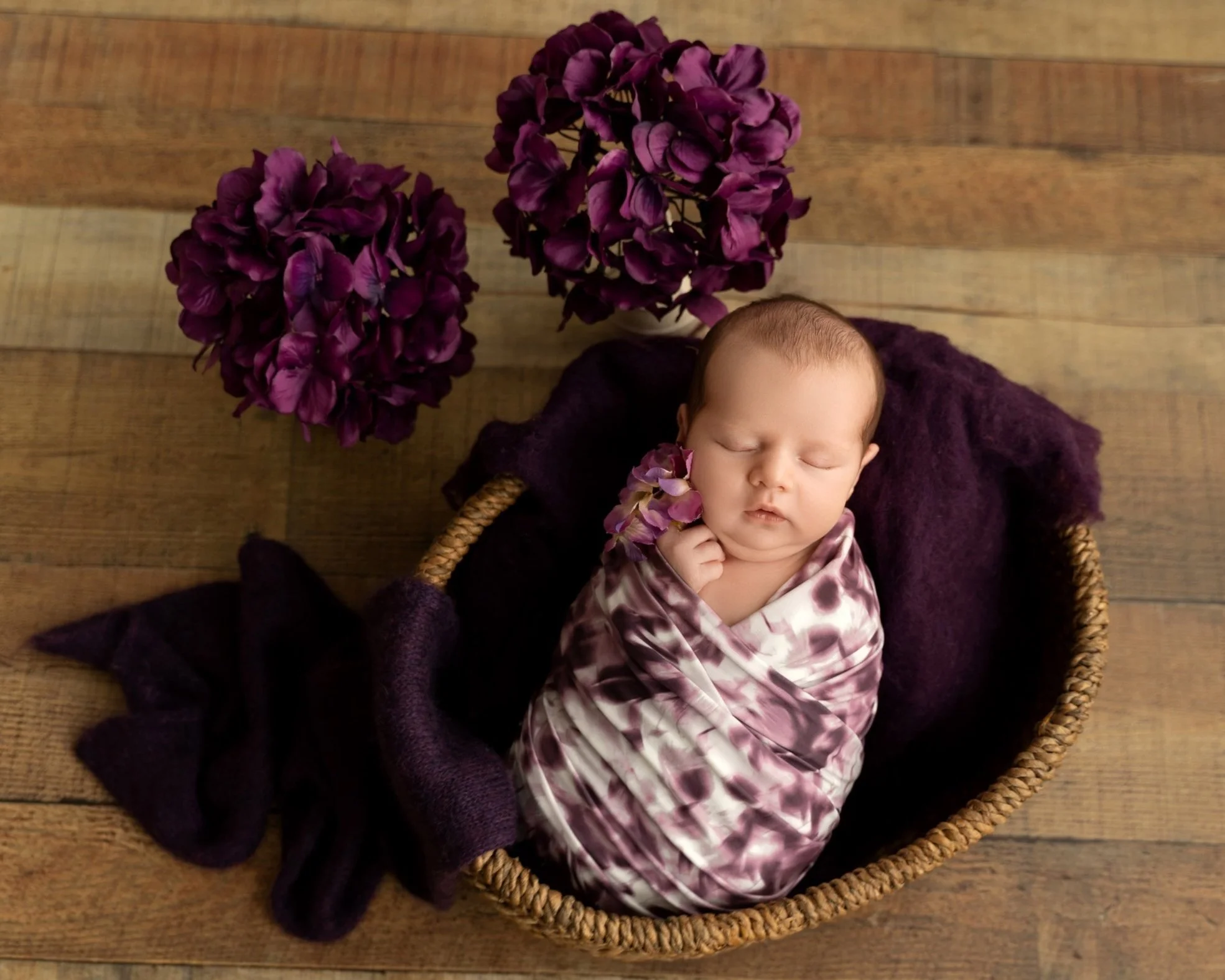 Tiny baby girl Grace holding a purple flower