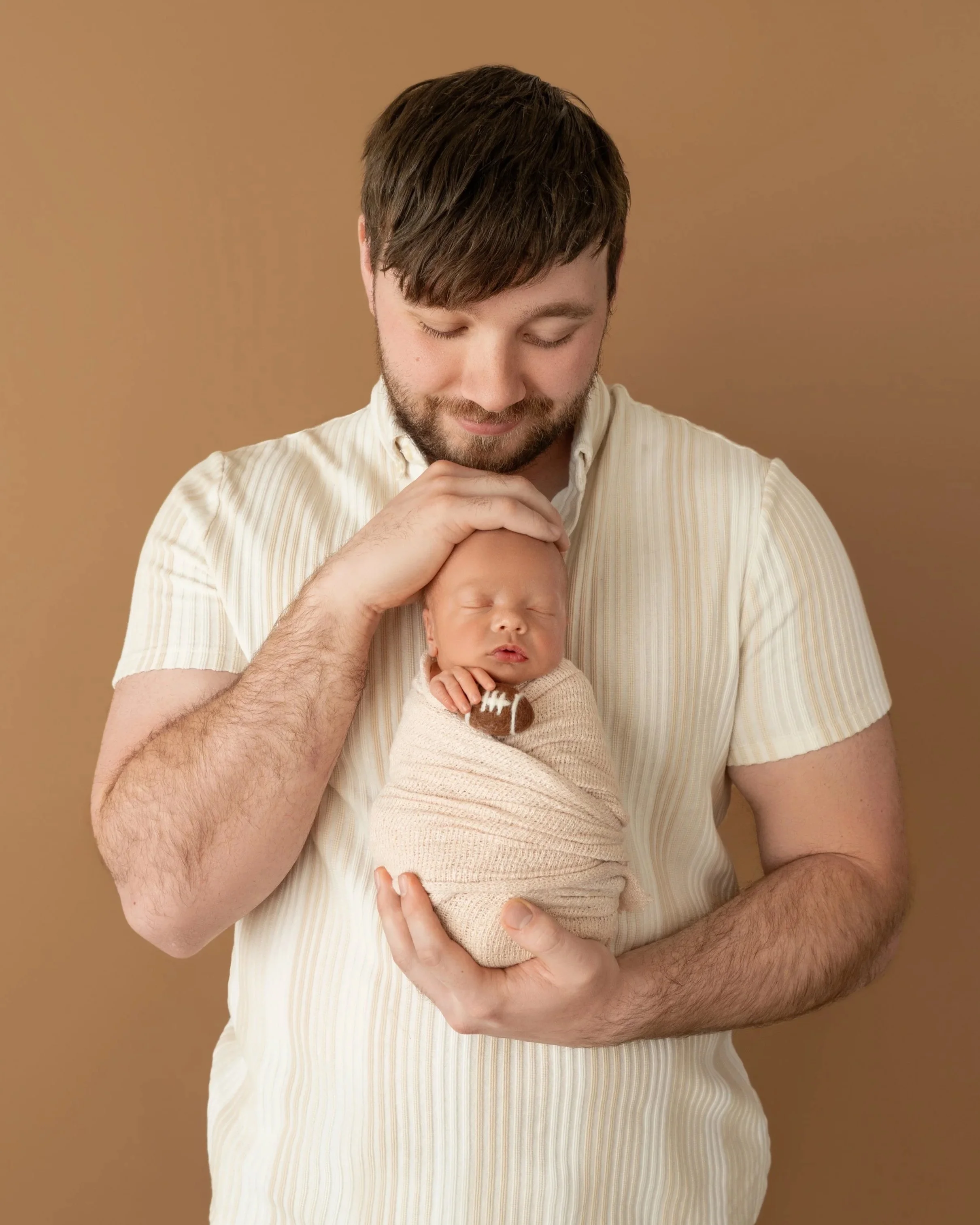 baby Nolan holding football with dad