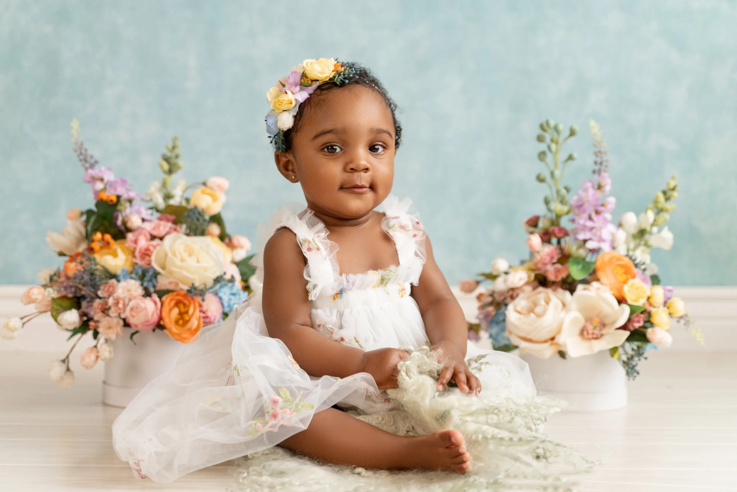 Soft floral setup for a baby girl’s one-year photos, featuring custom handmade decorations.