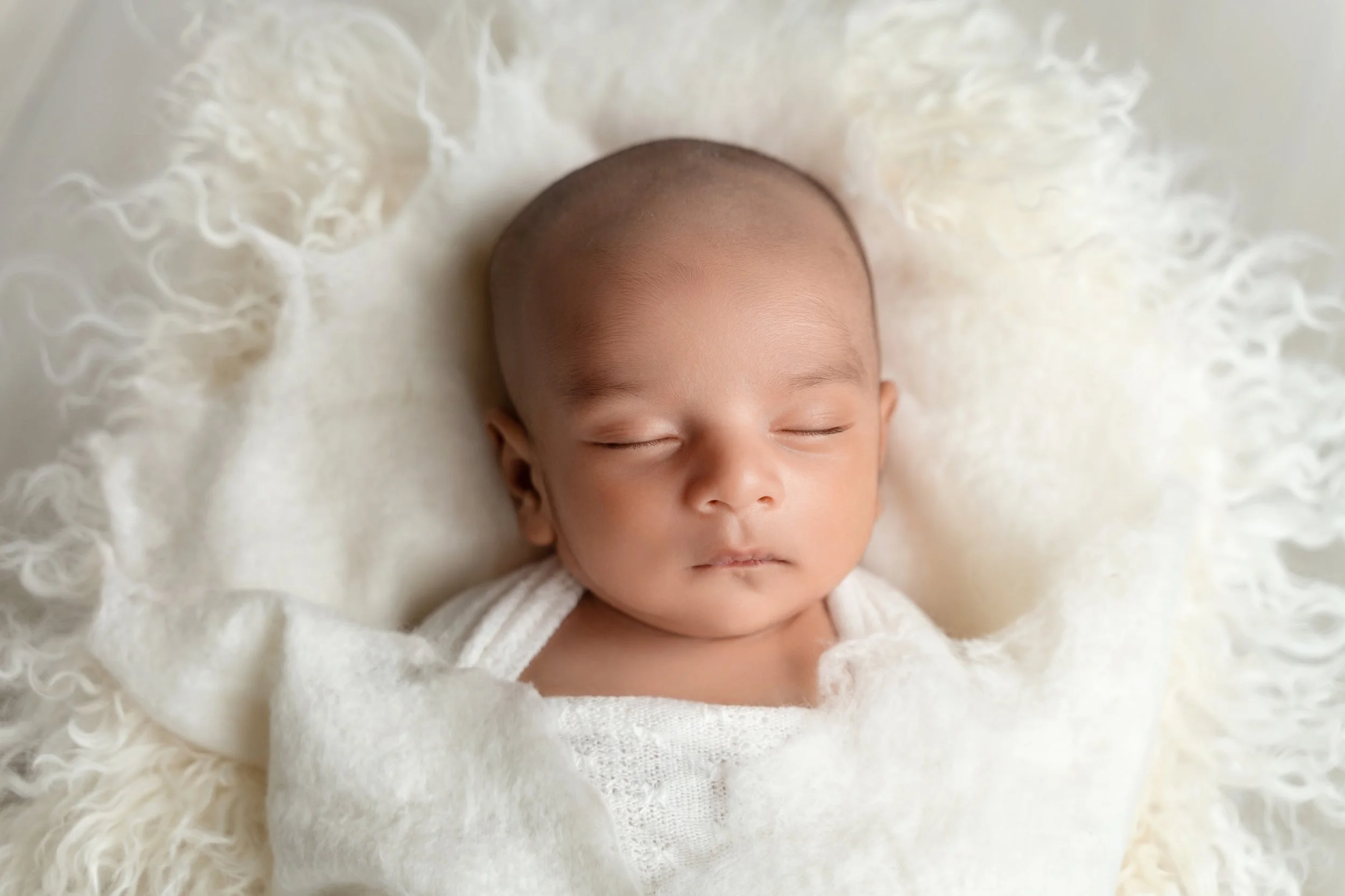 Baby boy Faiz peacefully sleeping during his newborn session with neutral colors and soft textures