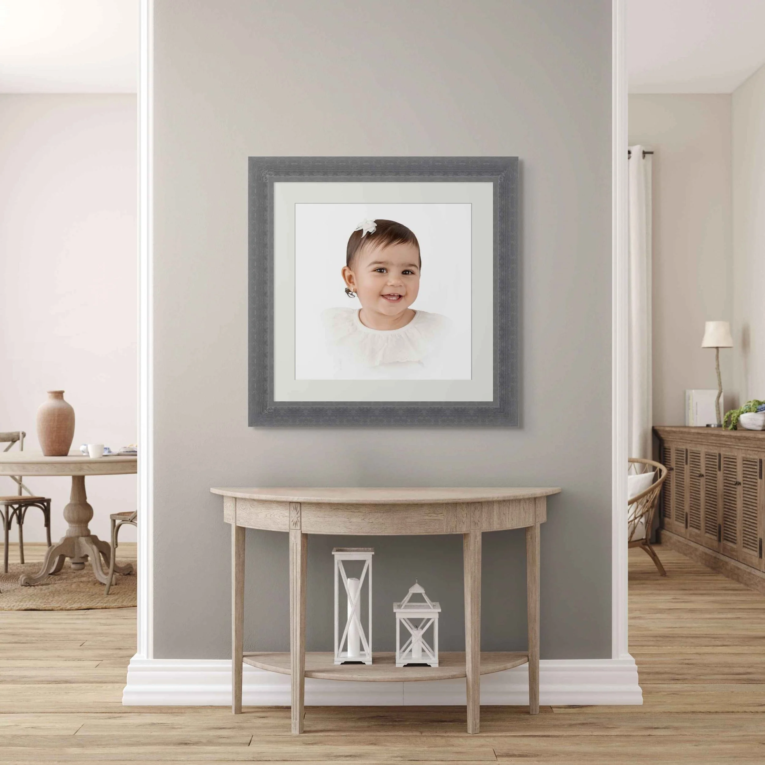 A framed artwork of a cherry blossom branch against a dark blue sky, leaning against a white wall on a wooden surface, with a bare decorative branch to the right.