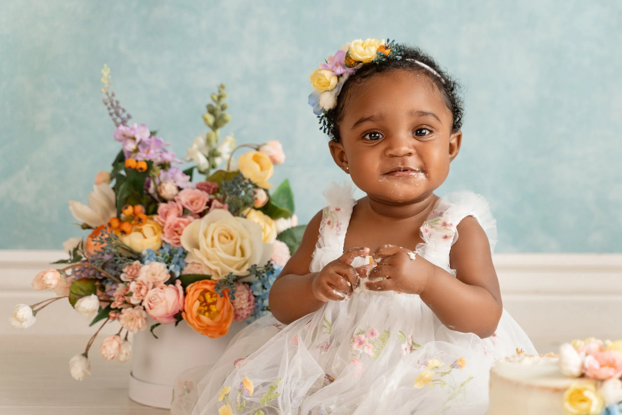 Close-up of one-year-old Ava tasting her birthday cake with a messy, joyful expression.