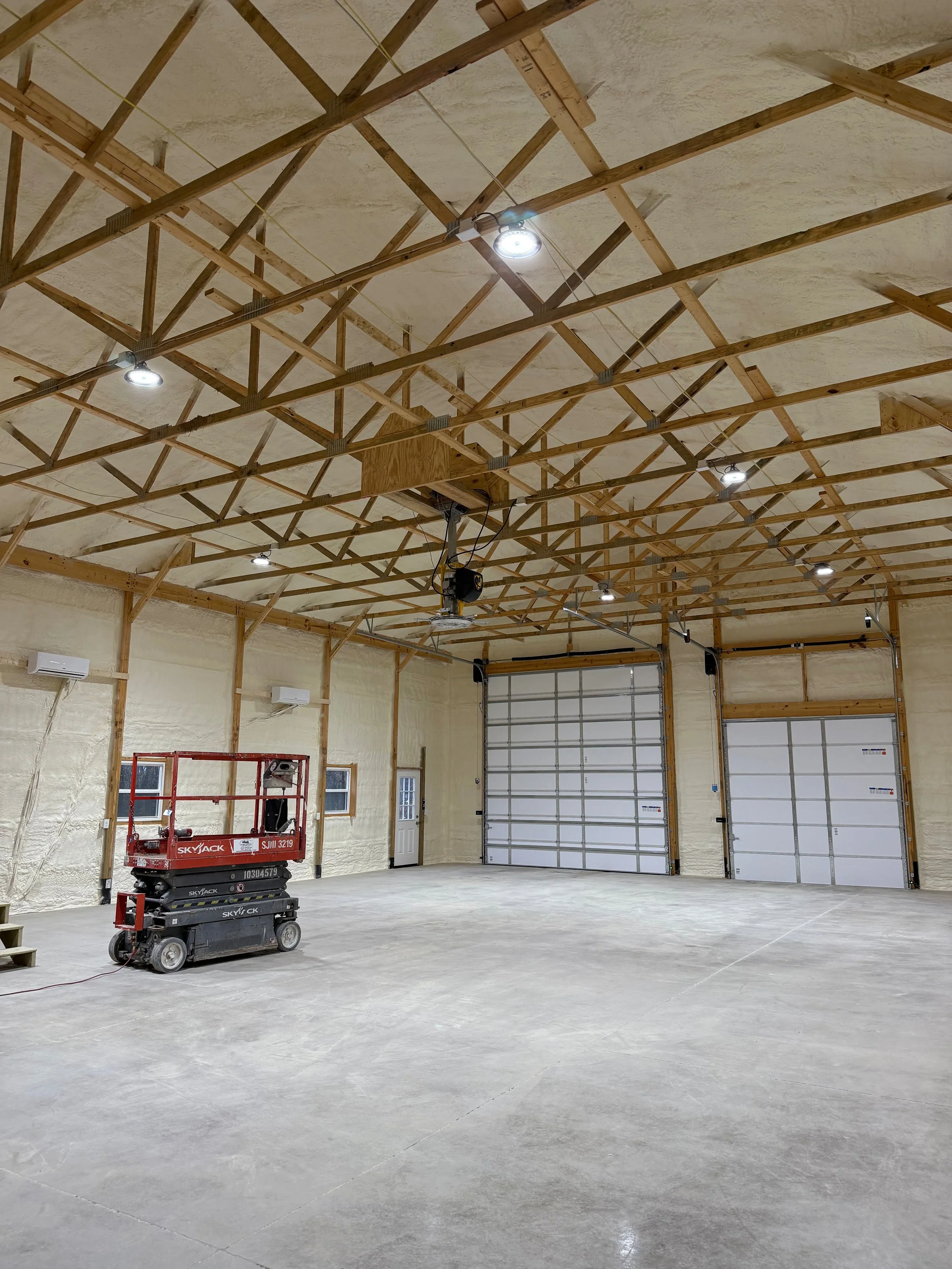 interior view of a commercial pole barn with spray foam insulation on walls and roof trusses under construction — Summit Sprayfoam, Ohio